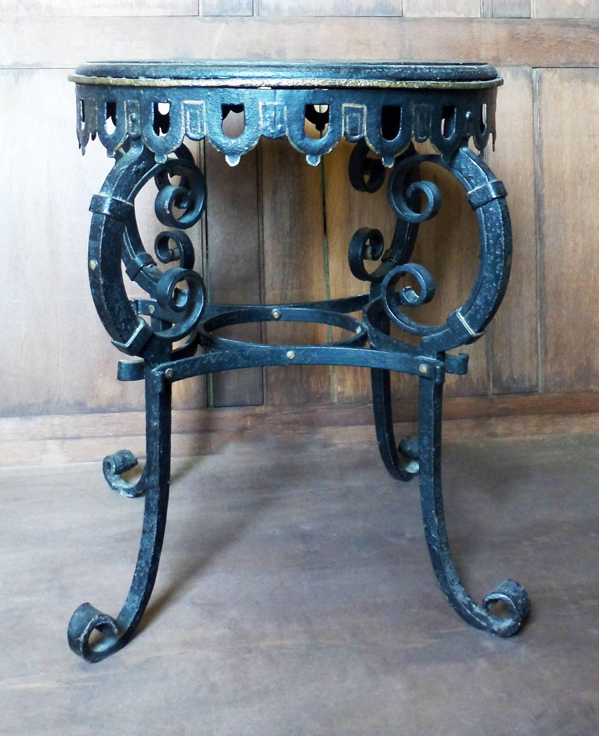 An antique French circular iron table, with four decorative scrolling iron legs and an iron strap and riveted form stretcher, circa 1870, France.