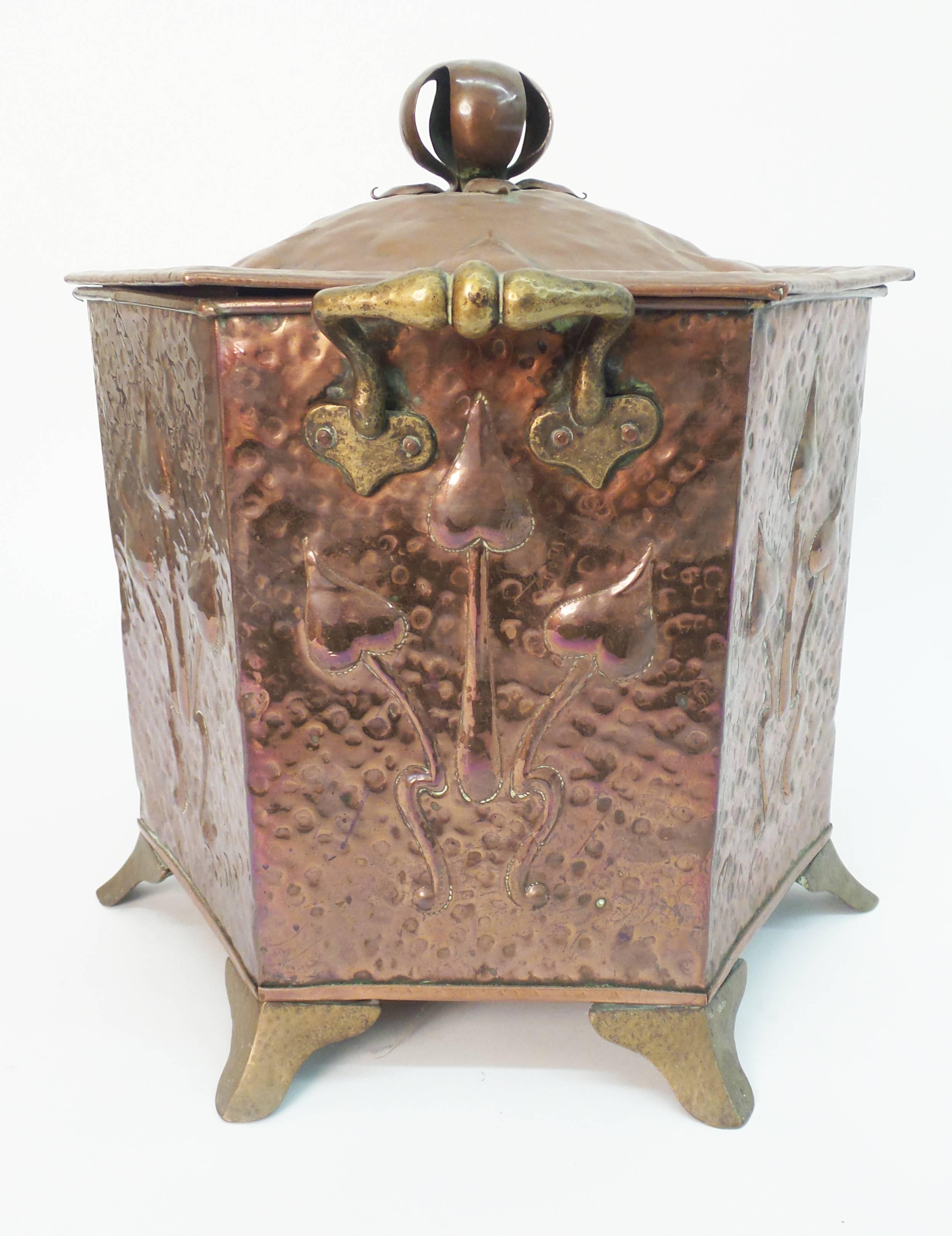 An Art Nouveau period hammered copper coal scuttle of hexagonal form and having brass feet and handles, England, circa 1885.