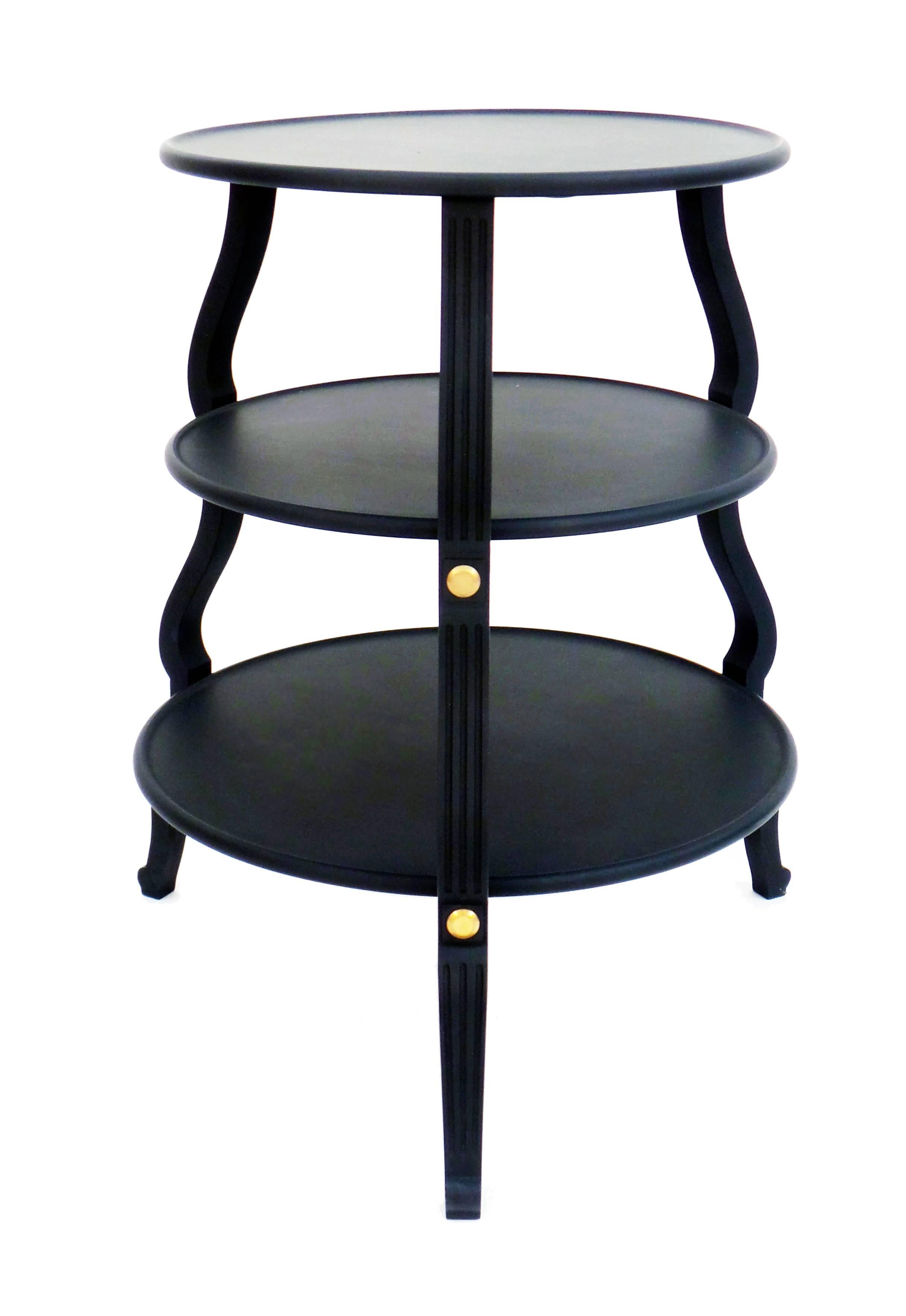 A circular side table with three floating tiers, each with tray-top surfaces, supported by 3 baluster-form fluted legs with custom brushed brass mounts. Shown in a matte-black lacquer finish. Custom dimensions, finishes, as well as coffee table