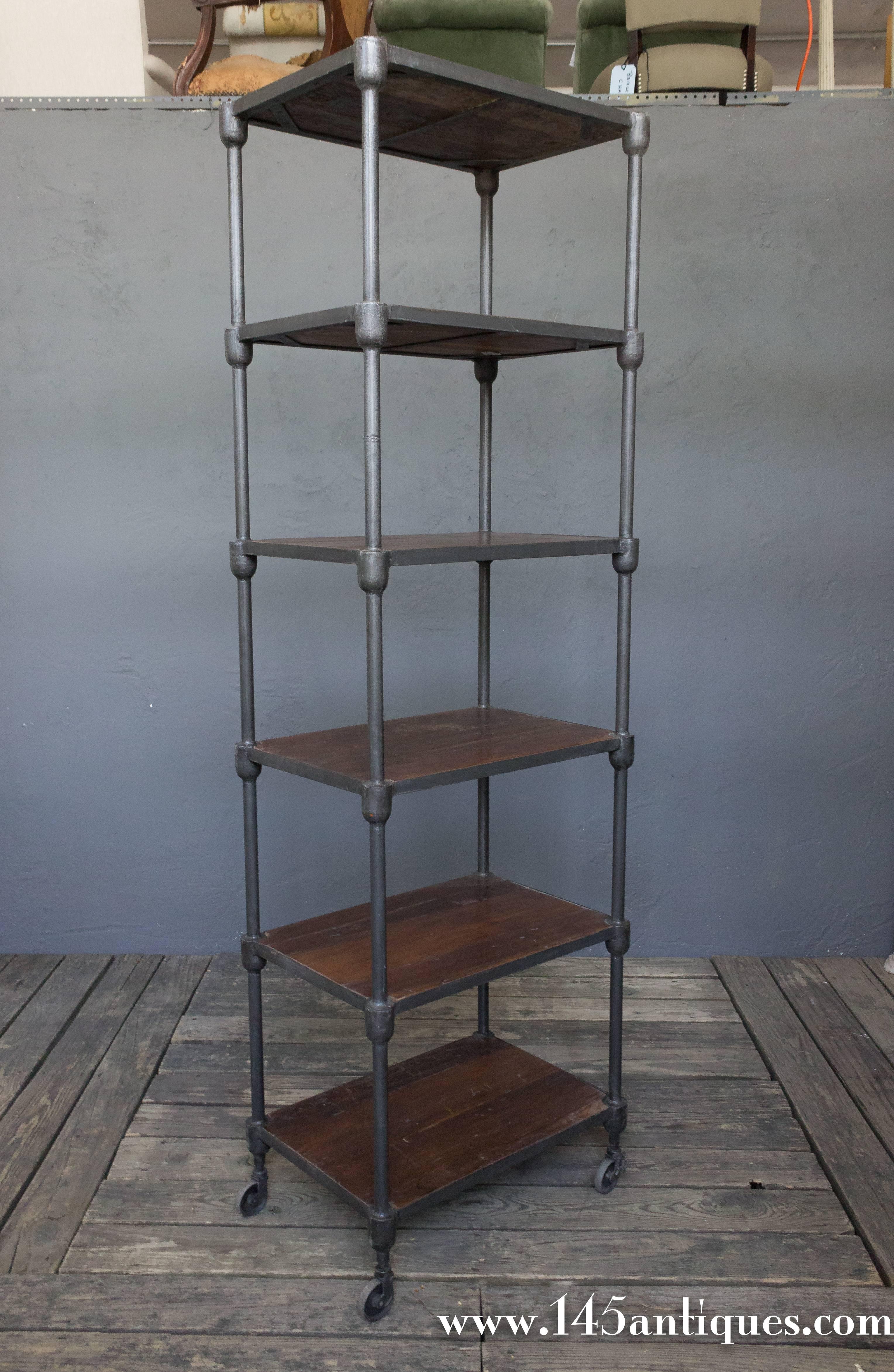 Handsome and practical etagere with a sturdy iron frame and wood shelves in an aged patina. The unit is on wheels and can be easily moved around, French, early 20th century.