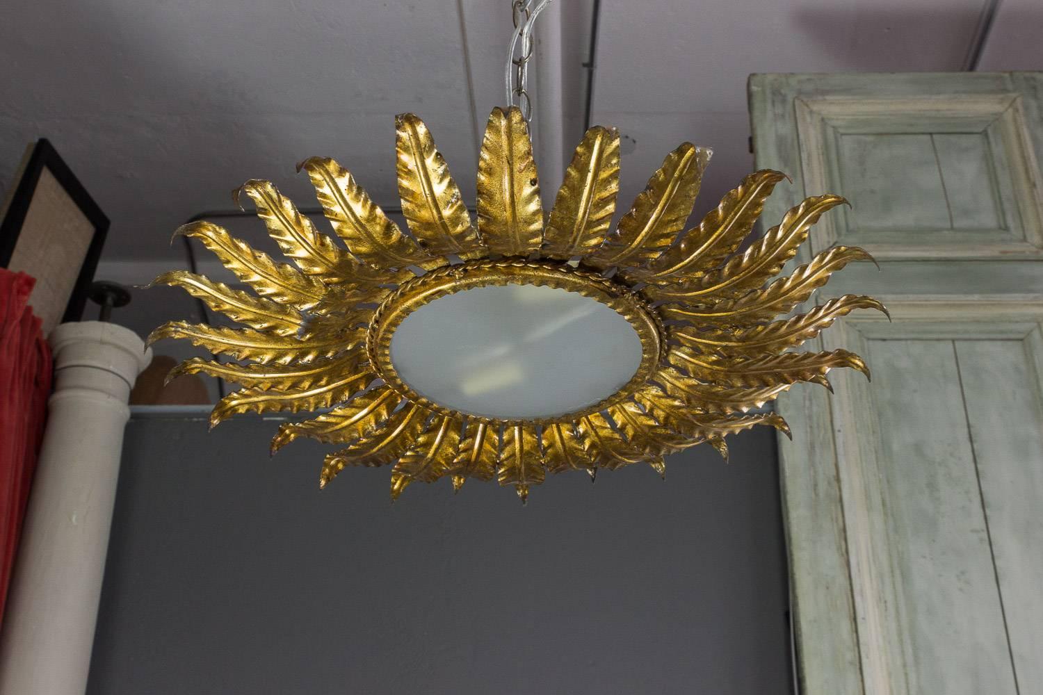 Spanish 1950s gilt metal ceiling fixture with radiating leaf motifs. The fixture has recently been rewired to accommodate two candelabra bulbs, and it is sold with a matching canopy. 

Ref #: LCF0516-03

Dimensions: 21.5