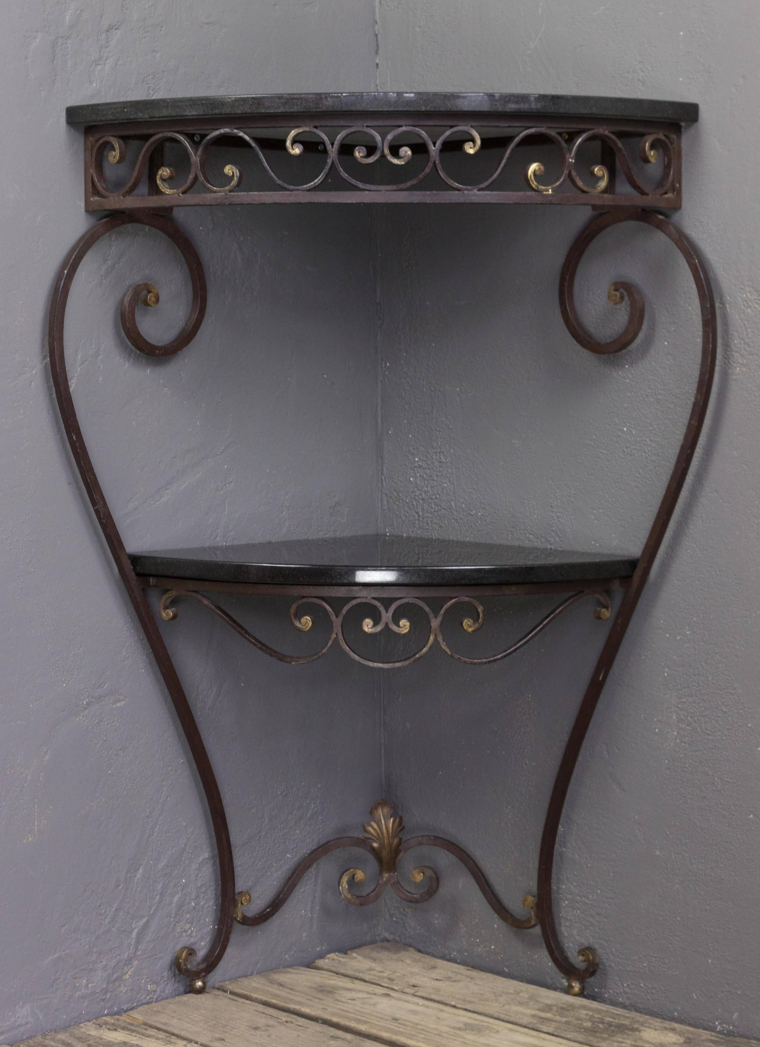 A handsome French 1940s wrought iron corner console with polished granite and traces of gilt to the frame. The console is in very good condition and the granite stone shelves are new. We think this unusual piece is perfect for that corner that needs