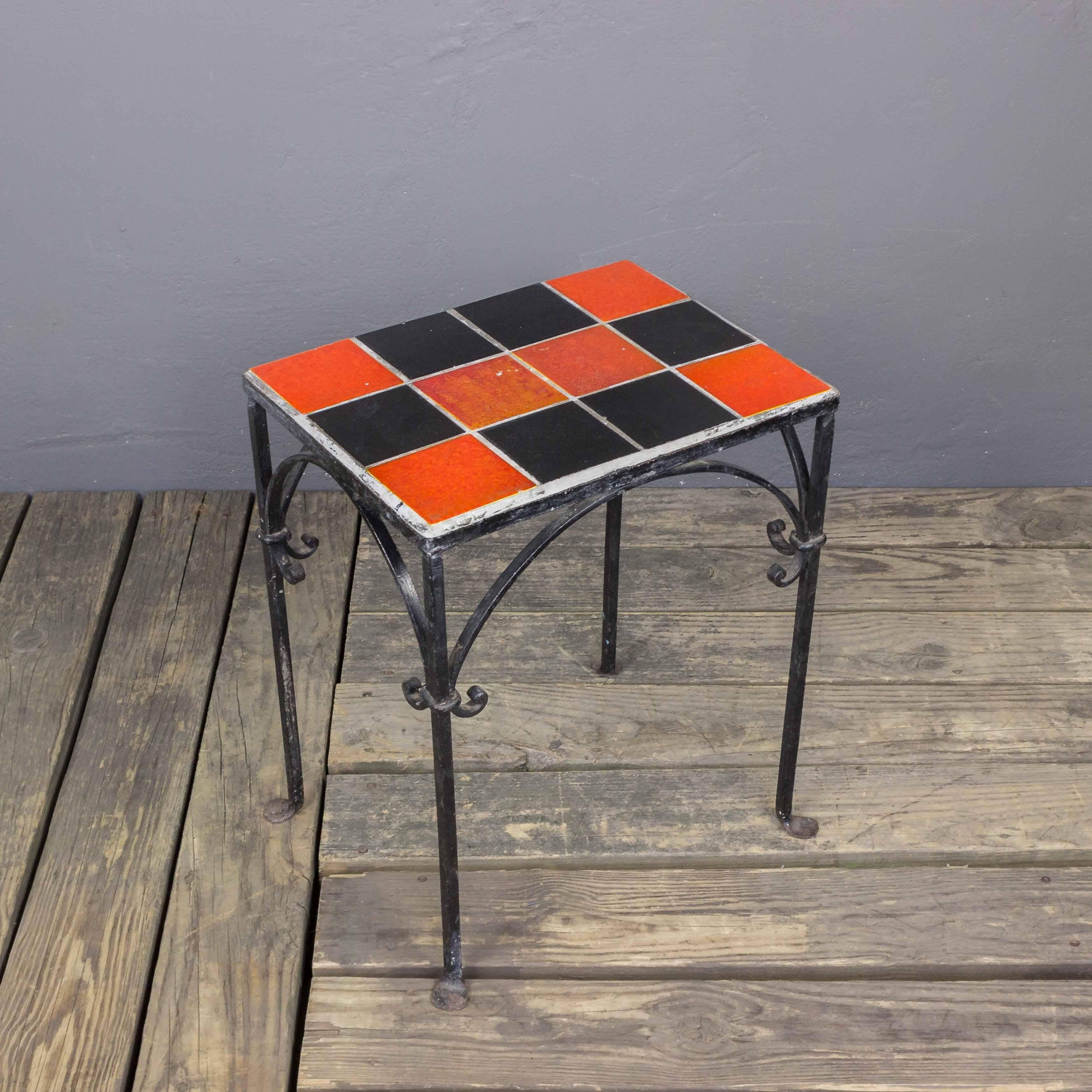 Iron side table with contrasting black and orange and red ceramic tiles. American 1950s.