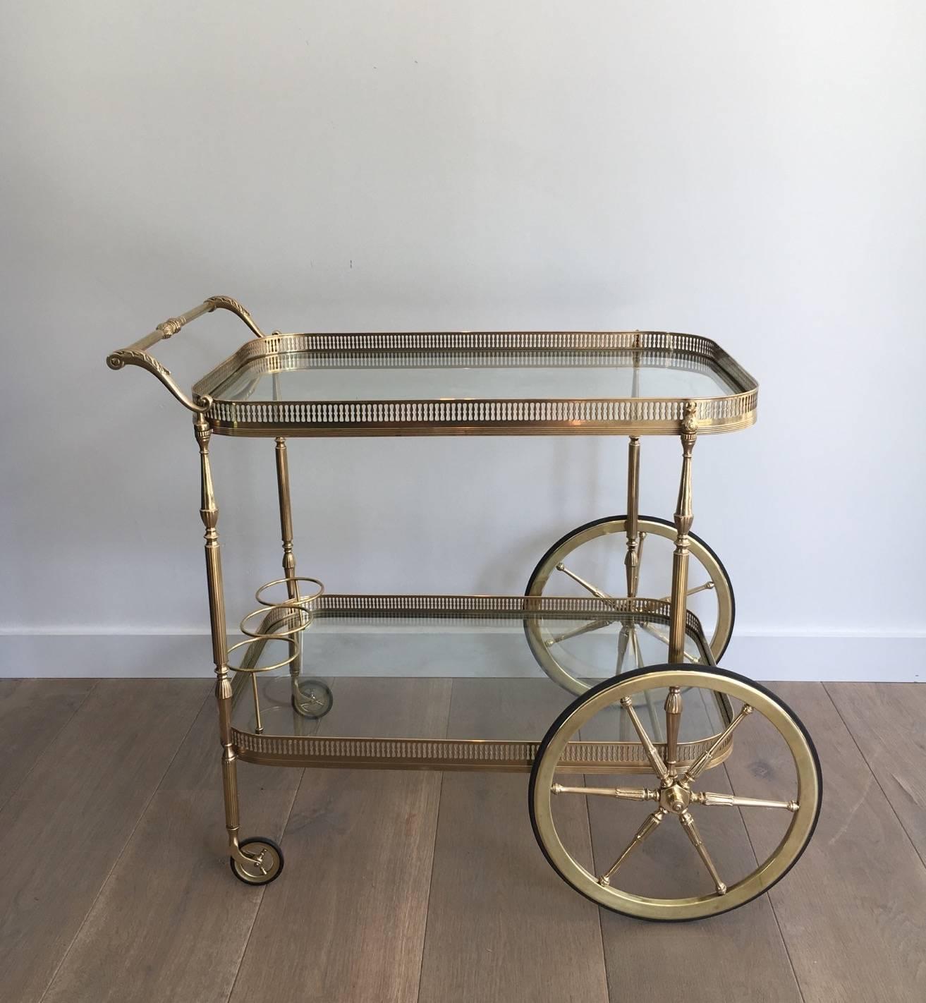 Excellent rolling brass bar cart with clear glass shelves in the neoclassical style.

This item is currently in France, please allow 2 to 4 weeks delivery to New York. 
Shipping costs from France to our warehouse in New York included in the price.