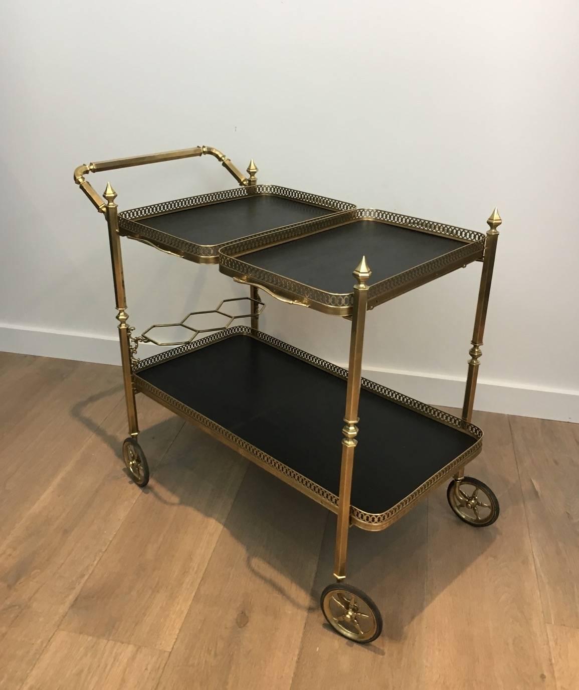 Neoclassical brass trolley with two removable black wooden and brass galleries trays on the top. It has four elegant wheels with a bottle well on the bottom tray, circa 1940.

This item is currently in France, please allow 2 to 4 weeks delivery to