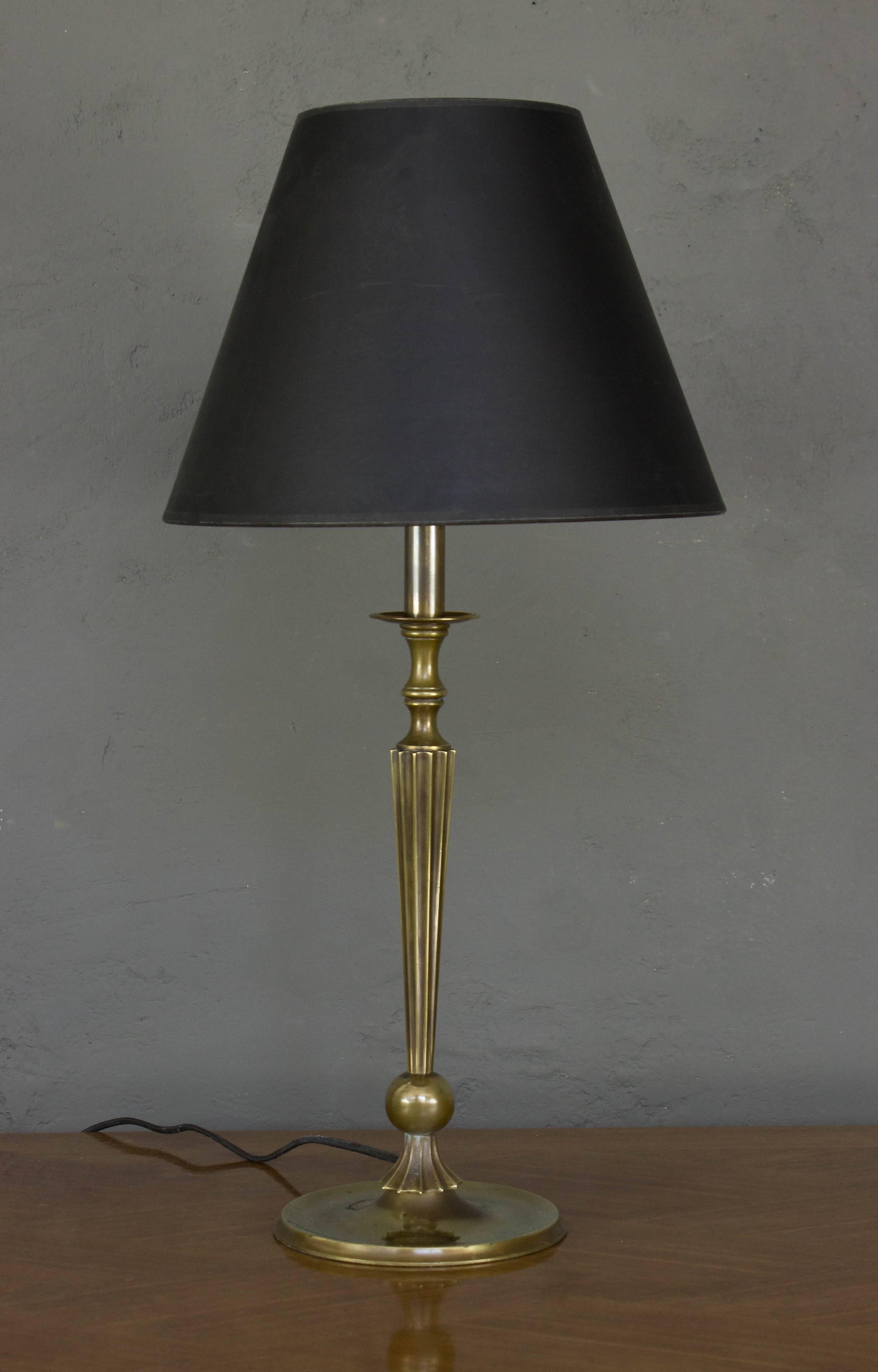 This pair of French 1940s brass table lamps embodies timeless elegance. These lamps feature fluted stems resting on ball and circular bases, showcasing exquisite craftsmanship from the era. Recently polished and rewired, they are in very good