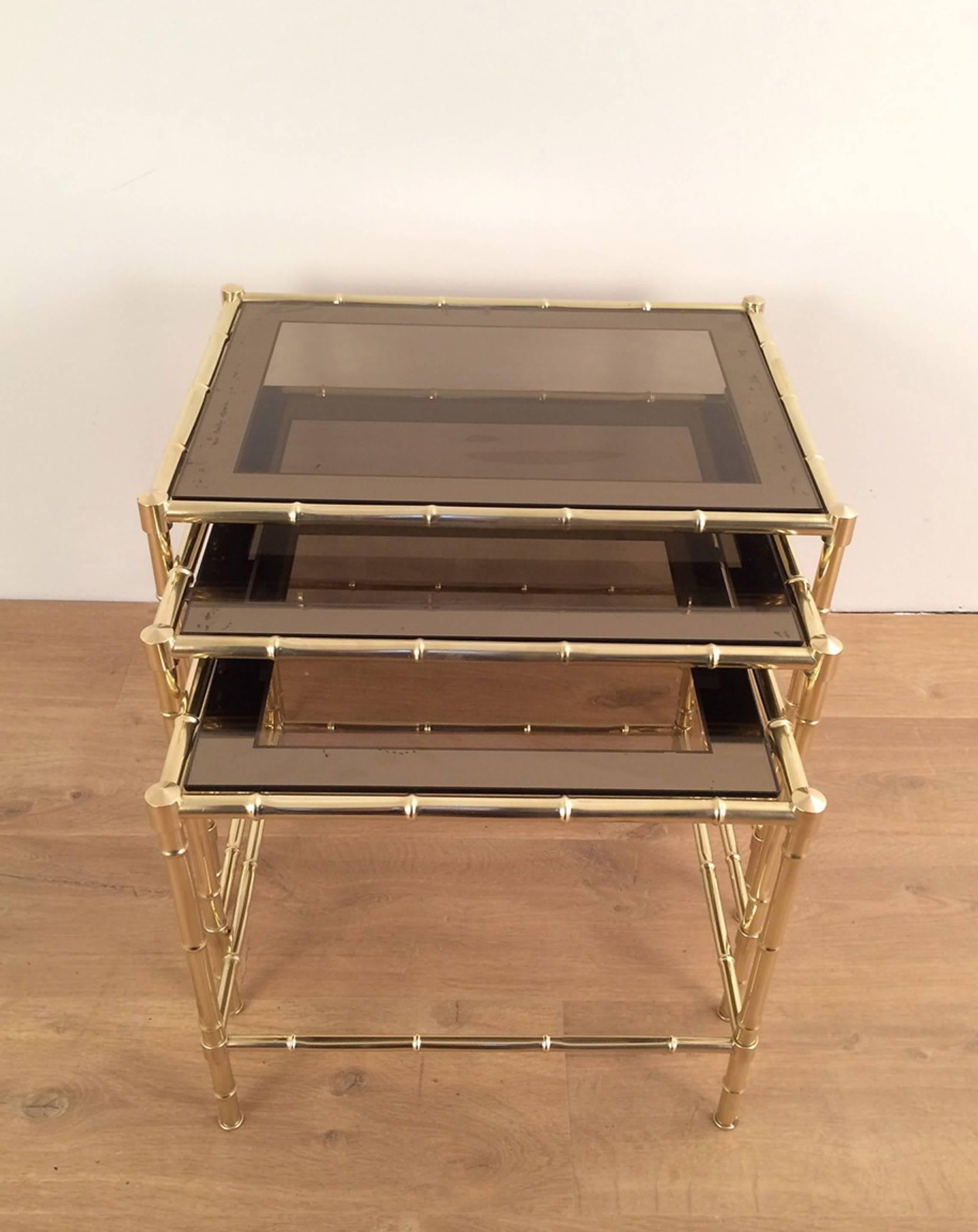 Set of three faux-bamboo brass nesting tables with smoked glass in the style of Jacques Adnet, French, circa 1960

These nesting tables are currently in France. Please allow us 4 to 8 weeks for delivery. Price includes delivery to our warehouse in