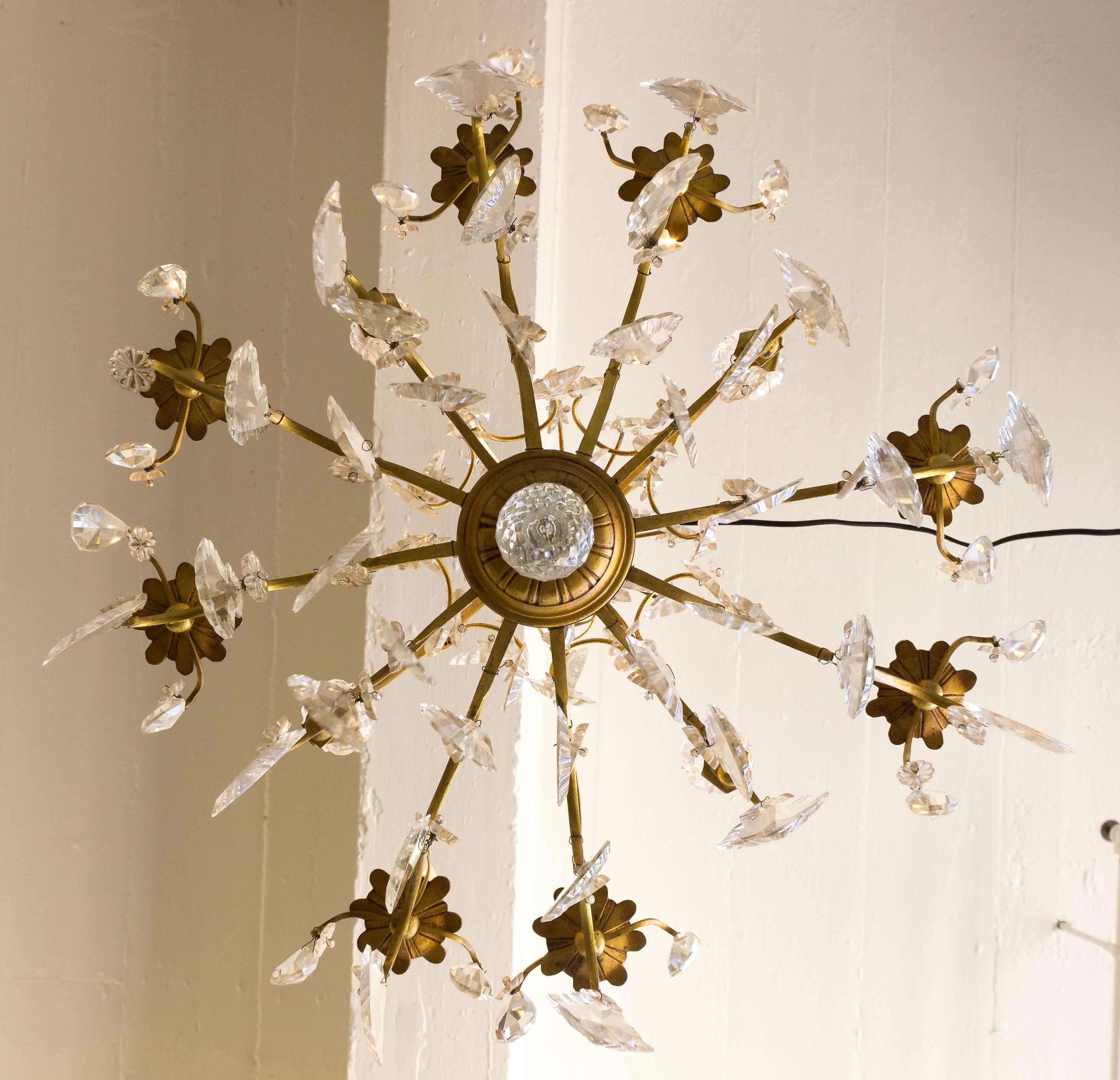 Presenting an elegant French 1920s gilt iron ten armed chandelier, this exquisite lighting fixture exudes sophistication and charm. Adorned with cut crystals, this stunning piece showcases the timeless beauty of the Art Deco era. Recently rewired,
