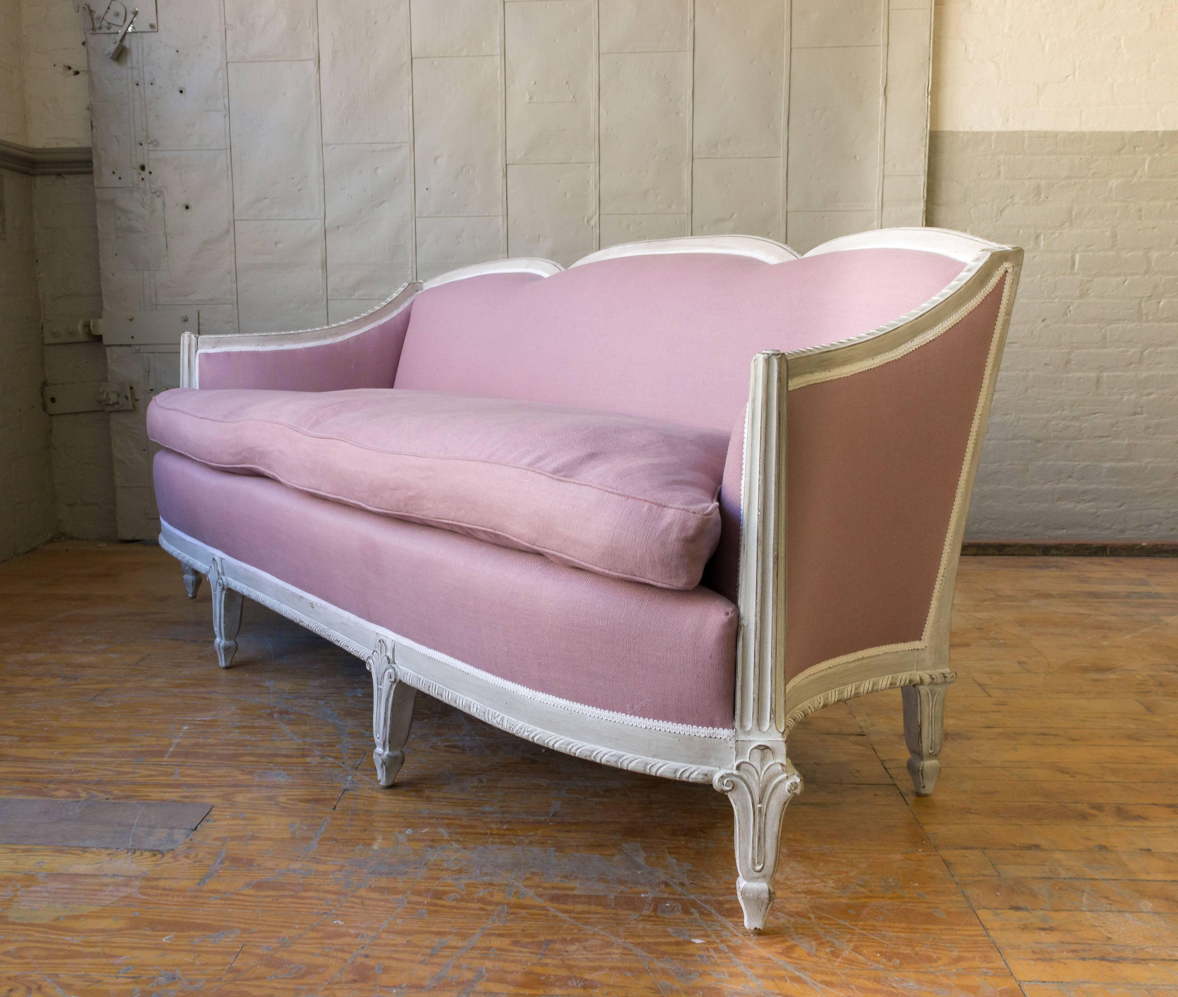 An elegant Art Deco style sofa with a patinated white -wash frame. The settee has recently been upholstered in lavender colored linen, having a very comfortable loose seat cushion. Possibly Italian, circa 1990s.