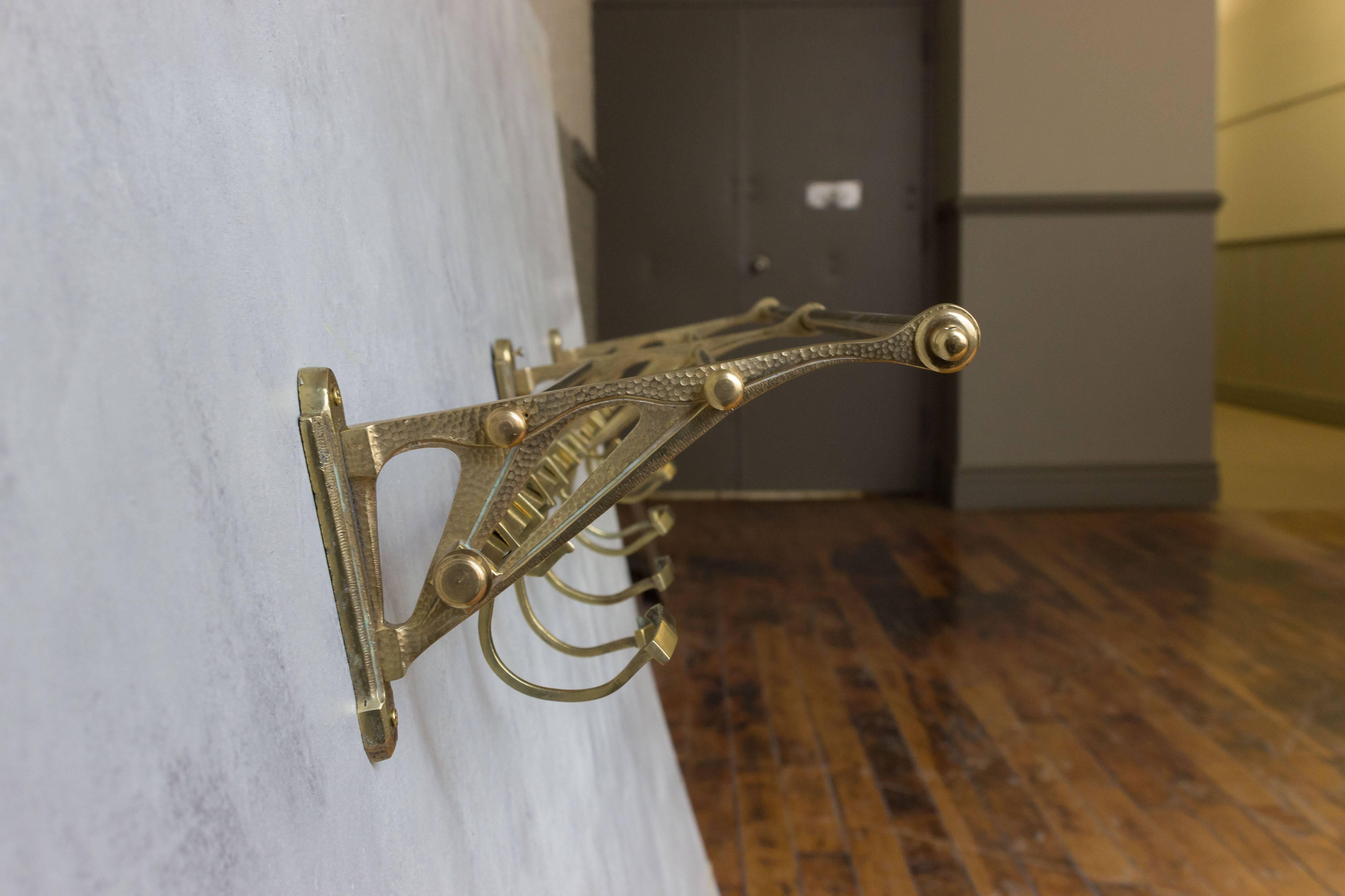 A brass coat rack with eight adjustable large hooks and four smaller ones. There is a top shelf for hats as well, French, 1920s.