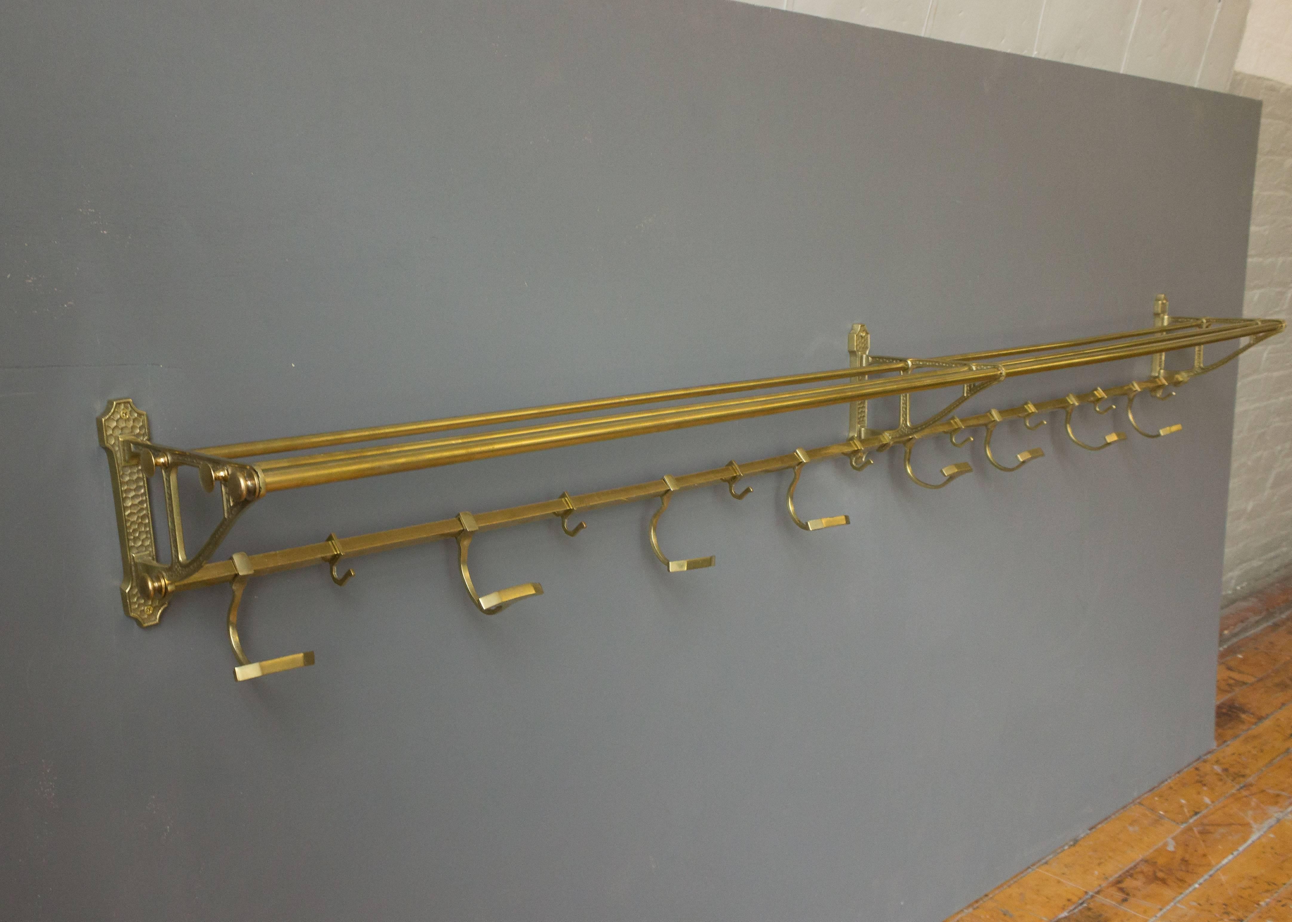 An exceptionally long brass coat rack with eight movable coat hooks as well as eight smaller scarf hooks. The top part is ideal for hats. French, 1920s.