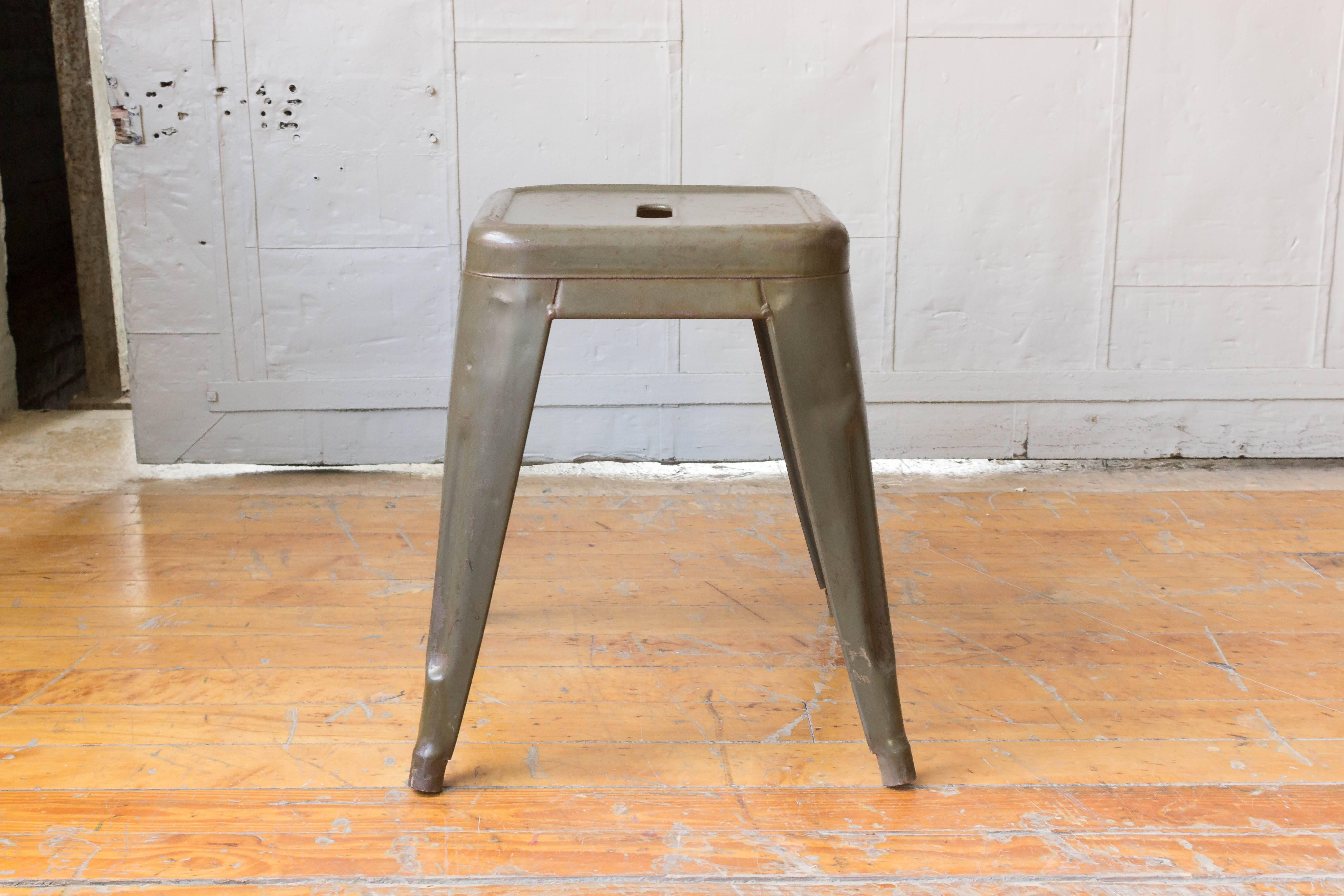 Set of six stacking metal stools with distressed green paint finish.