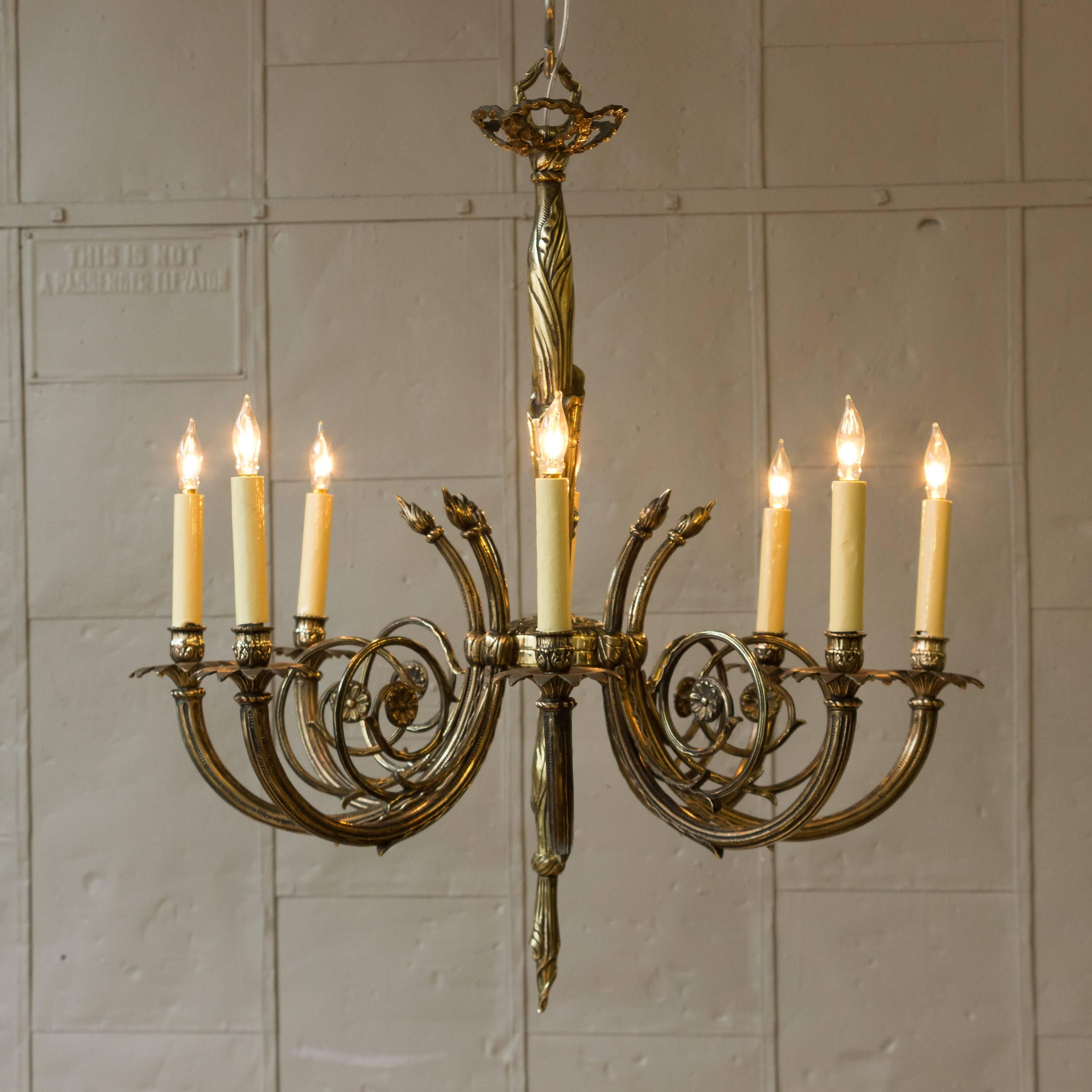This beautifully detailed 1920s French Art Deco style chandelier is made of brass with bronze components. This elegant chandelier is composed of eight spiraling arms and the center stem has stylized drapery details. In very good vintage condition,