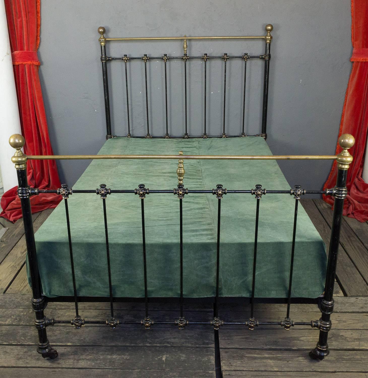 French 1920s black iron bed with brass detailing and casters.

 