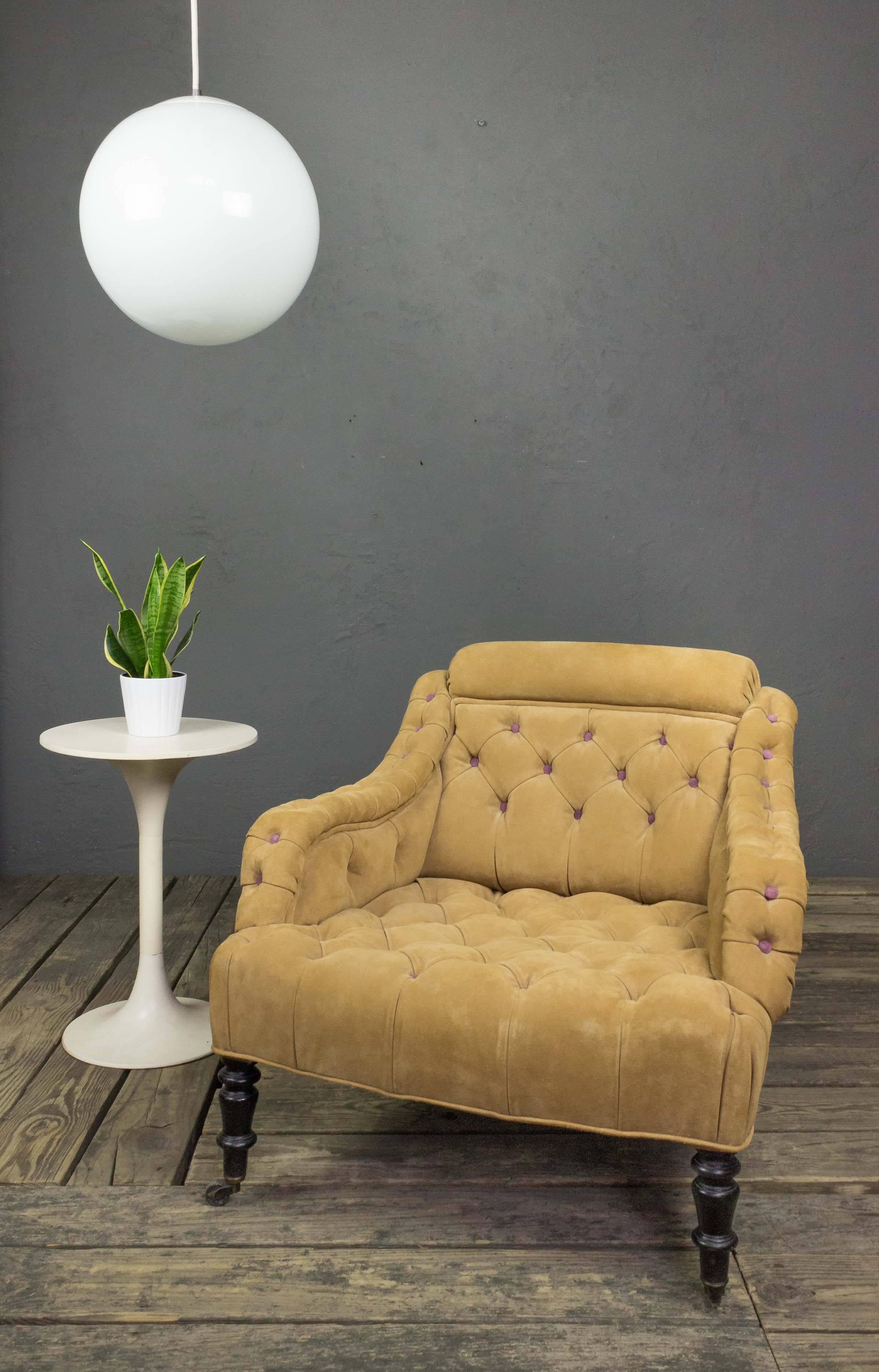 This French 19th century armchair is a one-of-a-kind piece. Its design is classic and timeless: tufted suede provides both visual appeal and comfort, while the rolled back ensures a secure seating posture. The chair is further accented with lovely
