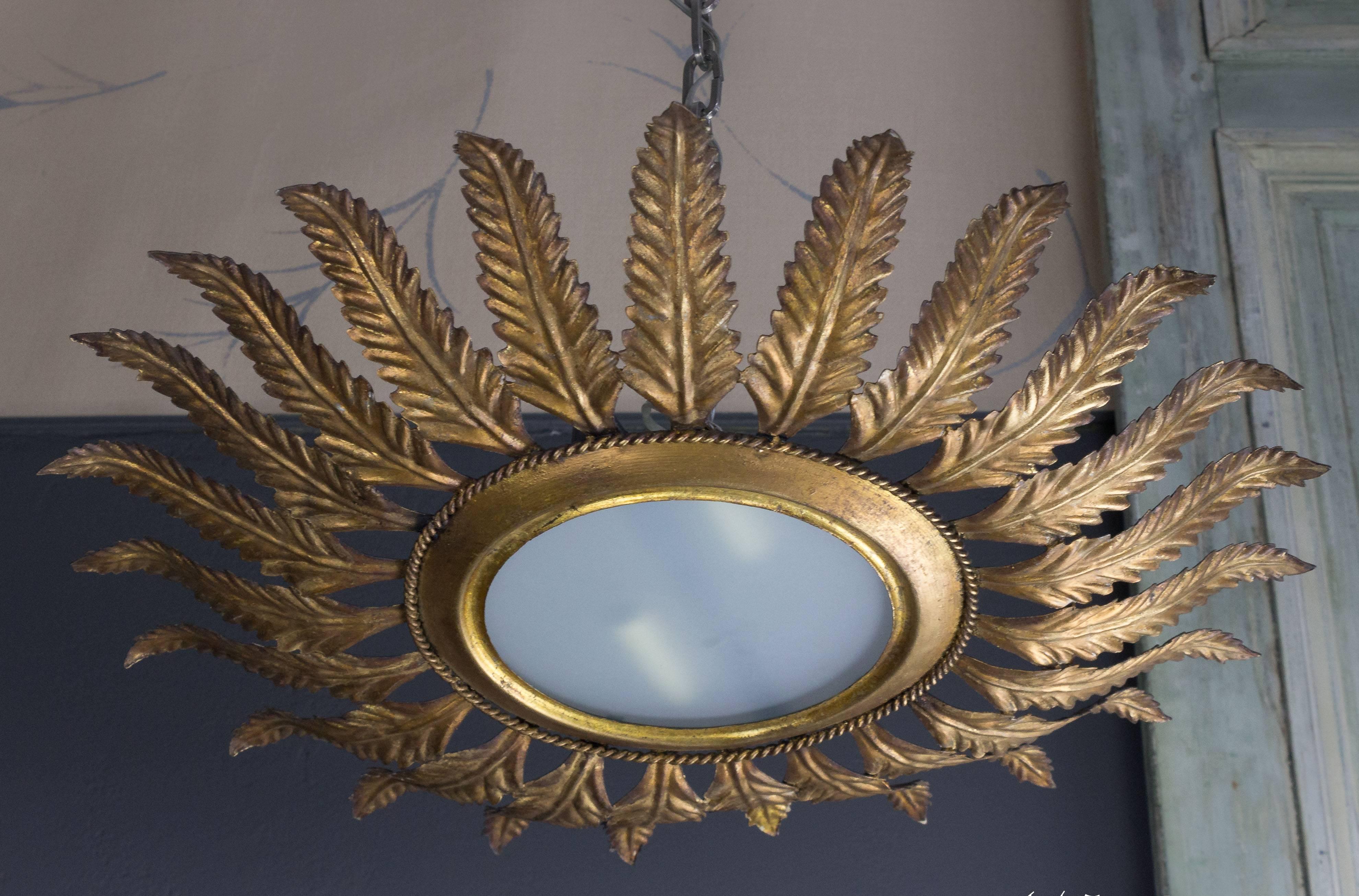 Spanish 1940s gilt sunburst ceiling fixture with decorative leaves connected to small braiding. Measures: 24