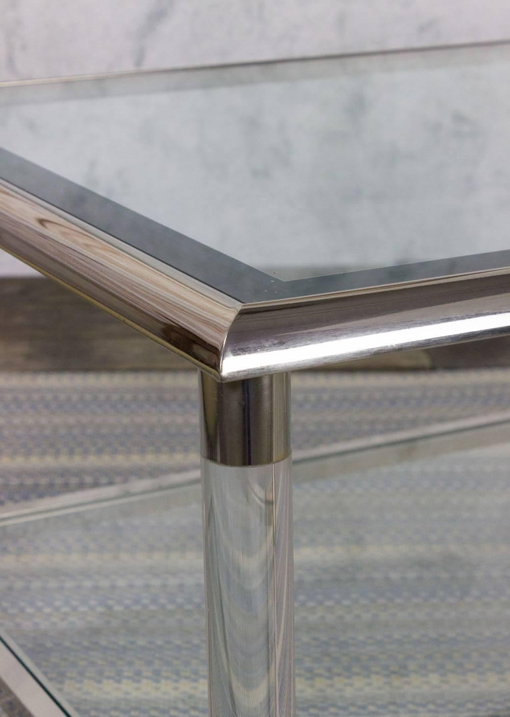 A handsome  French coffee table from the 1980s, featuring a lucite and chrome frame that exudes modern elegance. This timeless piece showcases beveled glass shelves, adding a touch of sophistication to its design. In good vintage condition, the