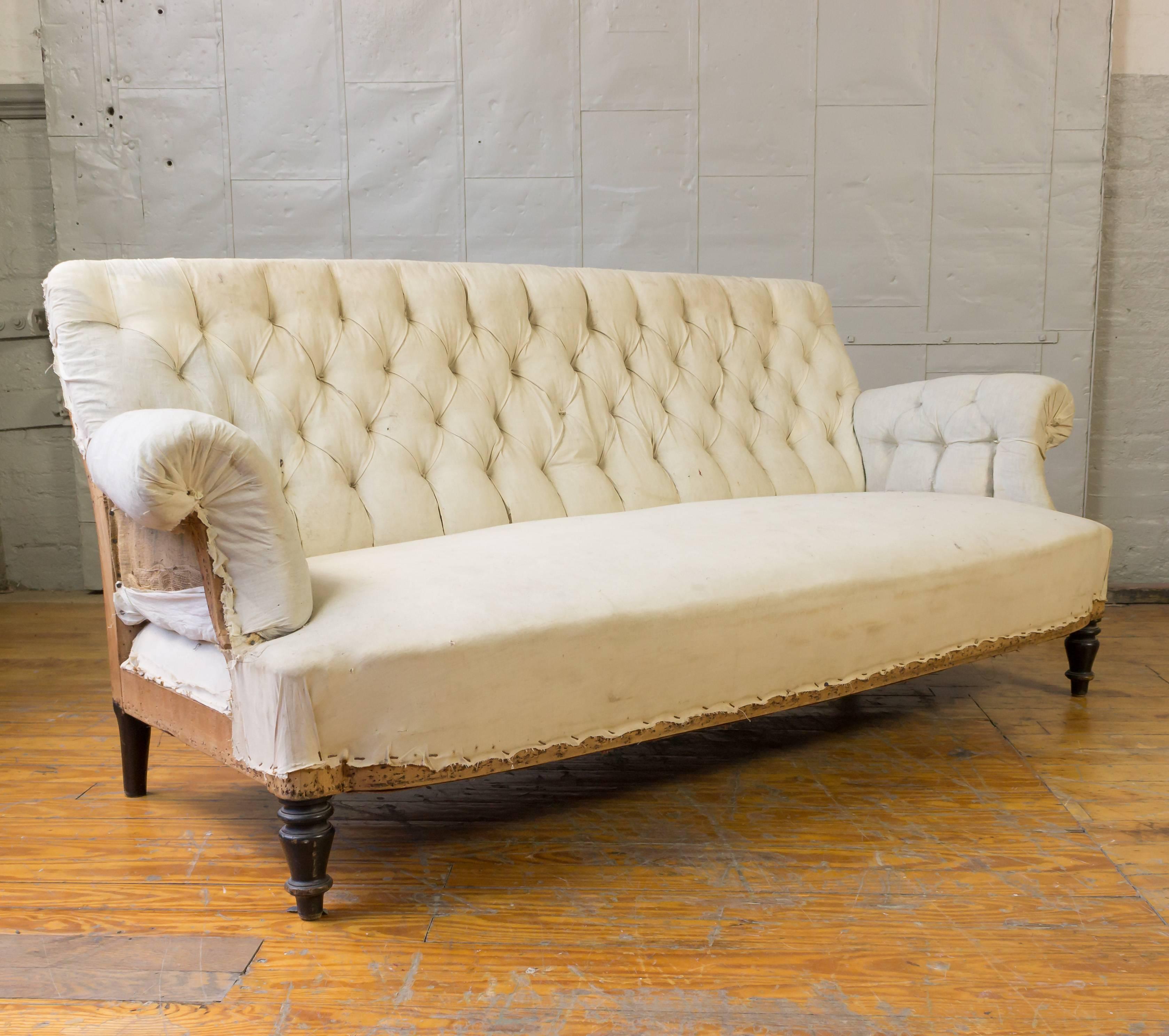 Napoleon III tufted sofa with rolled arms in muslin. Price includes refinishing of legs. This piece is very good condition with no work needed prior to upholstery. 

For upholstery service, labor cost is $1600 and 13 yards of solid fabric