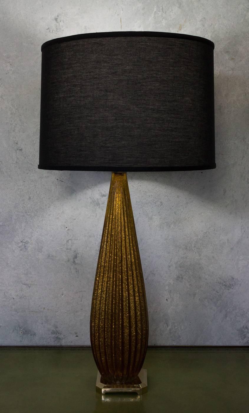 A stunning tall Italian Murano glass lamp with gold flecks inside the ribbed glass. This Italian Murano glass lamp is truly exquisite. The ribbed glass design of the lamp is unique and eye-catching, while the gold flecks inside the glass add a touch