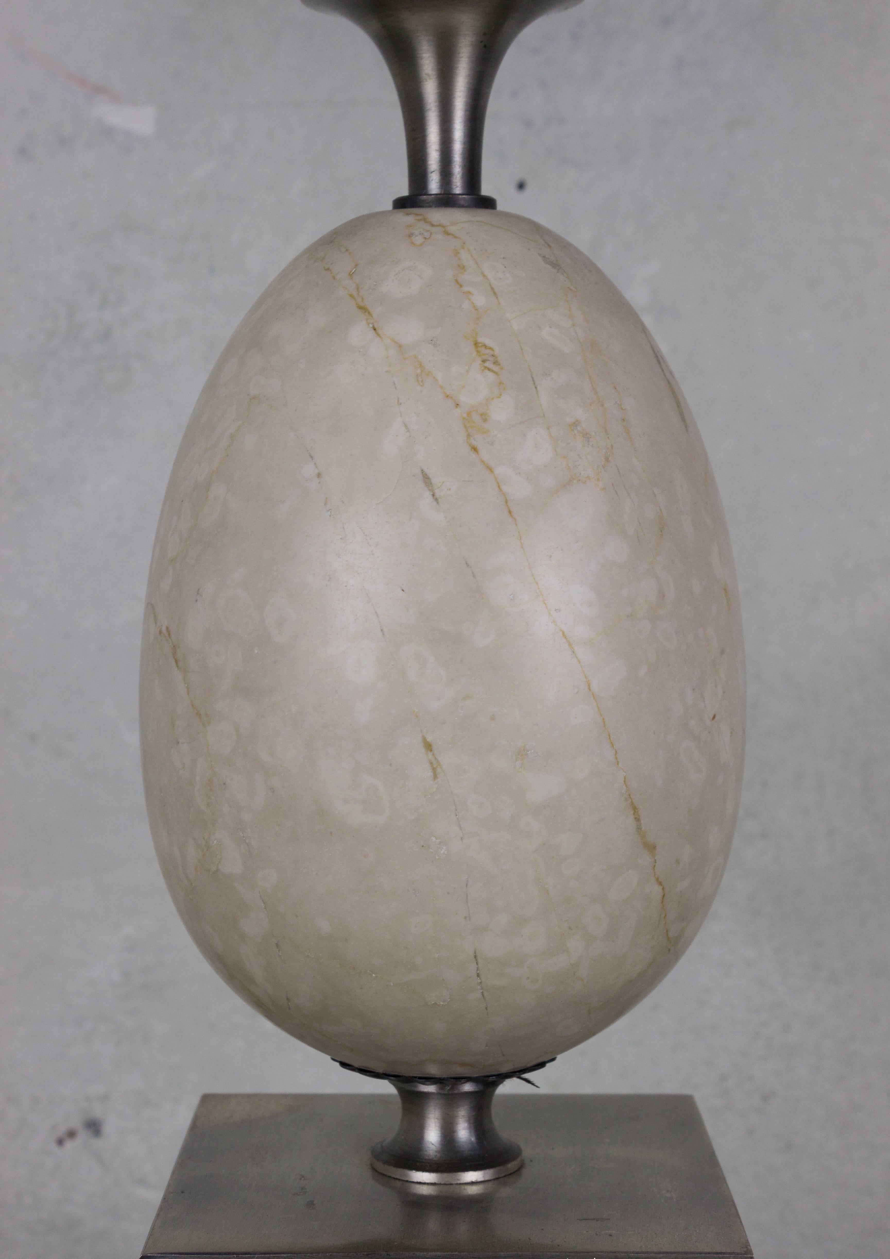 This French table lamp from the 1960s embodies elegance and sophistication. This handsome lamp takes the form of an ostrich egg, delicately carved from marble and perched atop a classical metal pedestal. The lamp has been newly wired and is in very