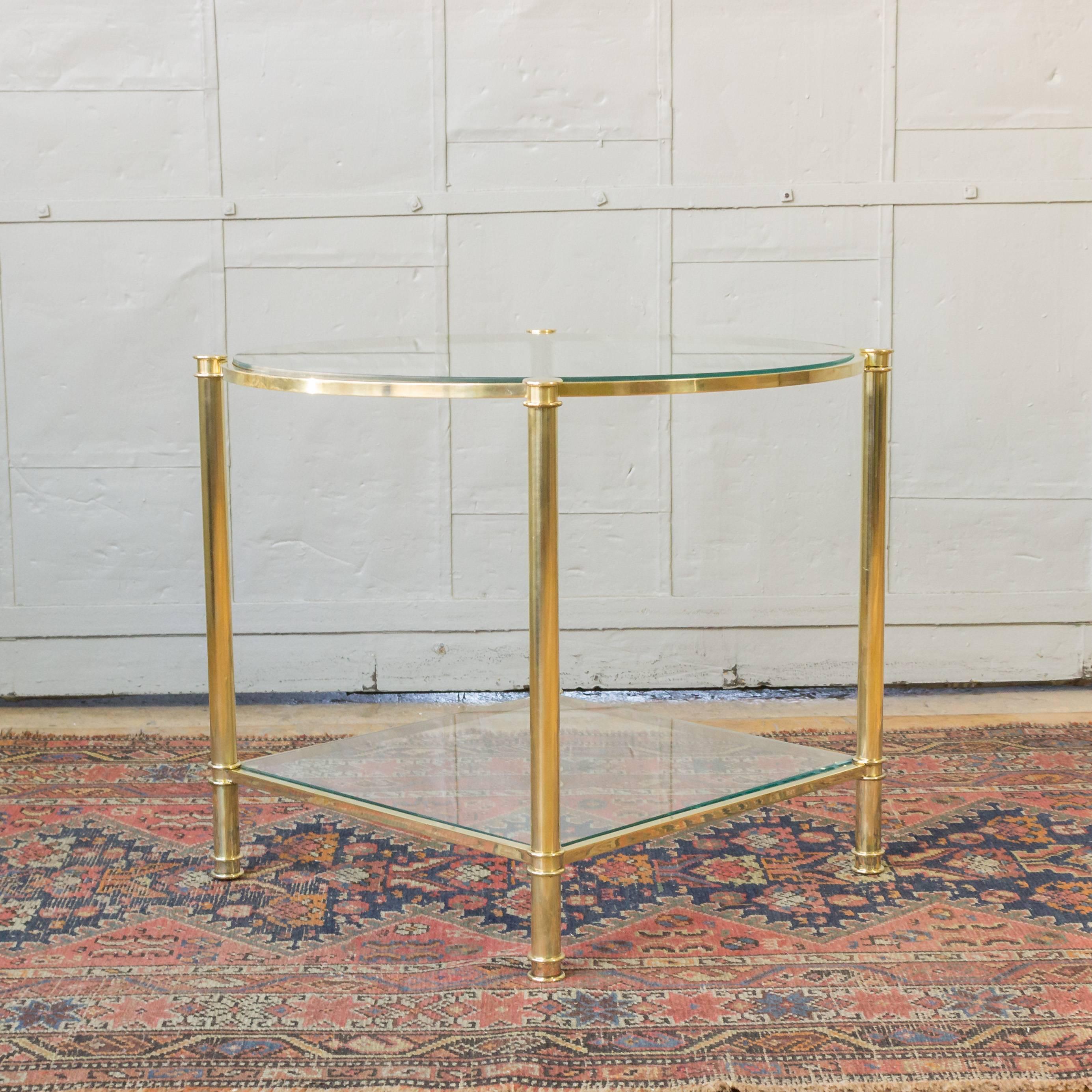 Pair of brass end tables, the top shelves are round and the bottom shelves are square. Made of polished brass and clear glass, French, 1970s.

