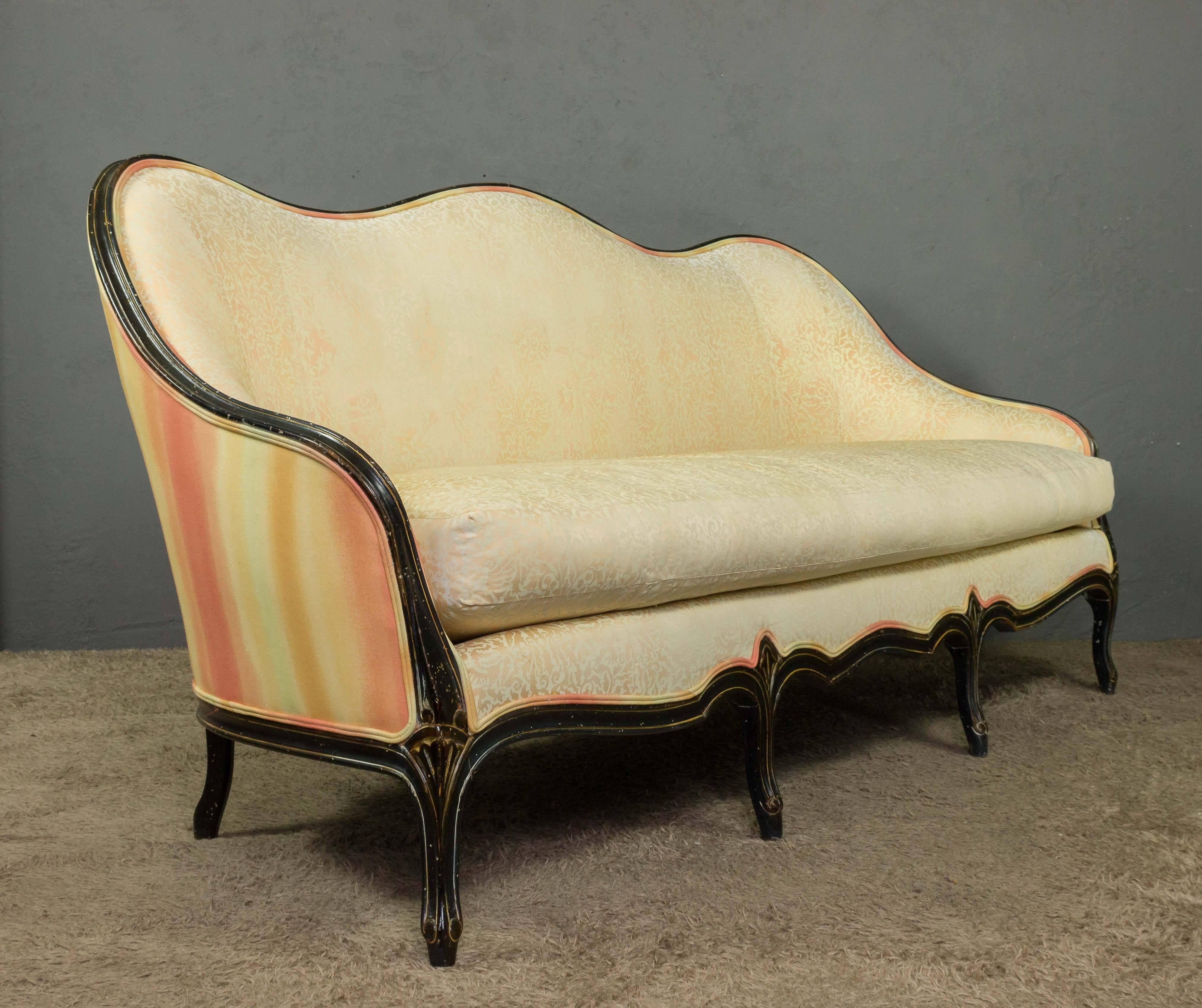 A large sofa with a loose seat cushion up holstered in a vintage multicolored fabric. The frame has a blackened patinated finish with contrasting carved and painted highlights. The sofa is very comfortable.  American, circa 1920.


