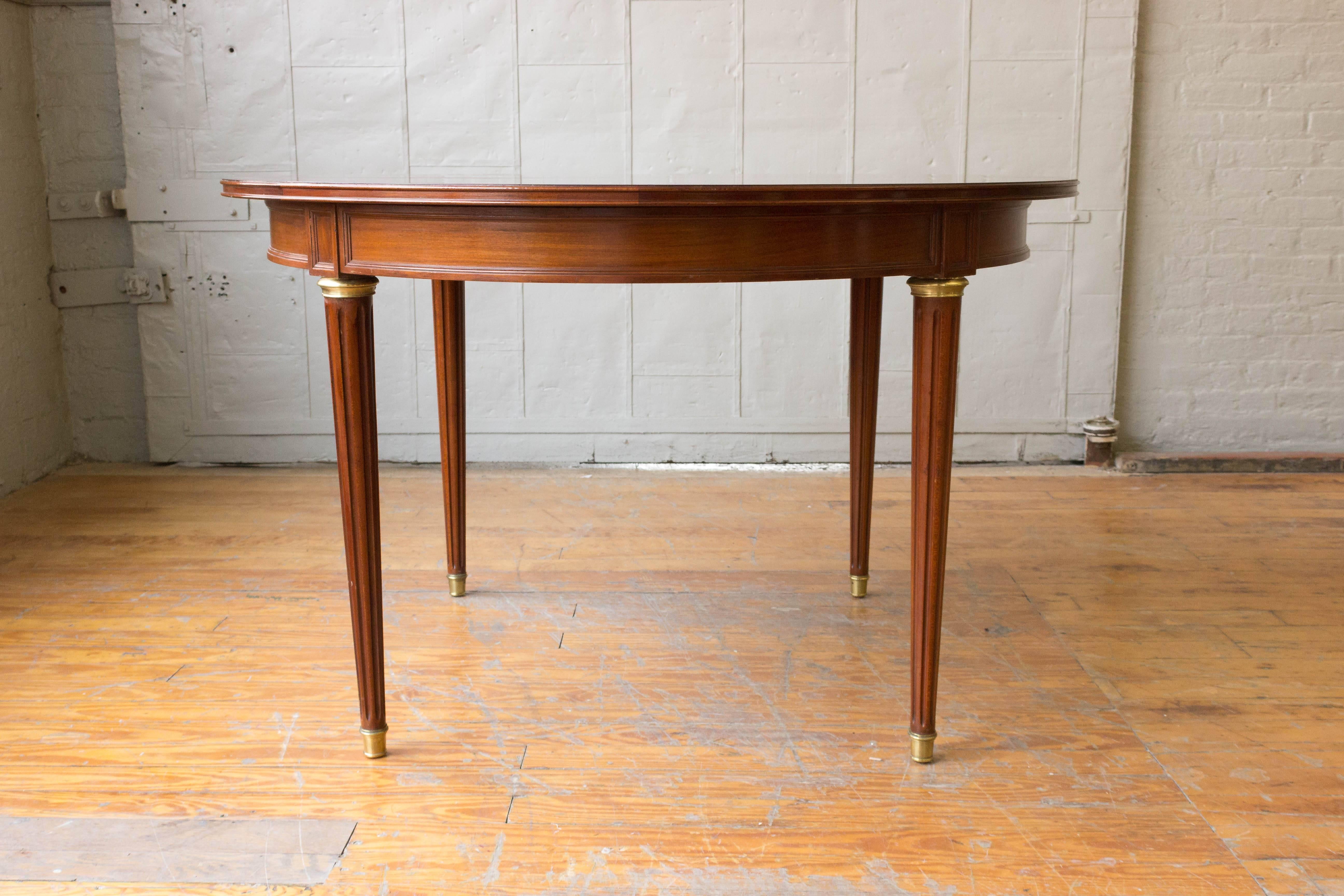 French 1940s mahogany oval dining table with tapered legs with brass sabots. Table sold with two leaves (19.75