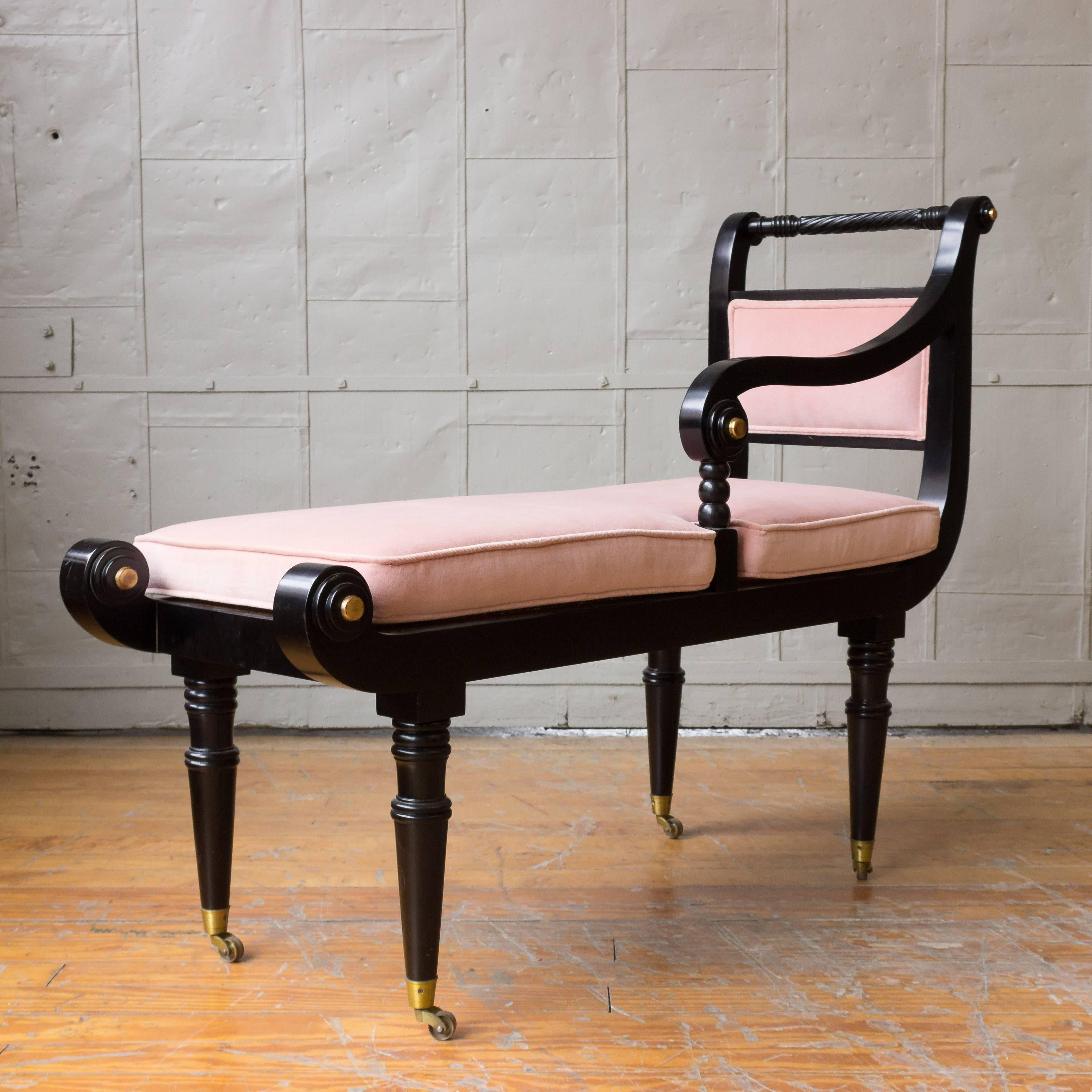 Ebonized Empire style bench with gold accents. The pink velvet cushion rests on a caned platform.
