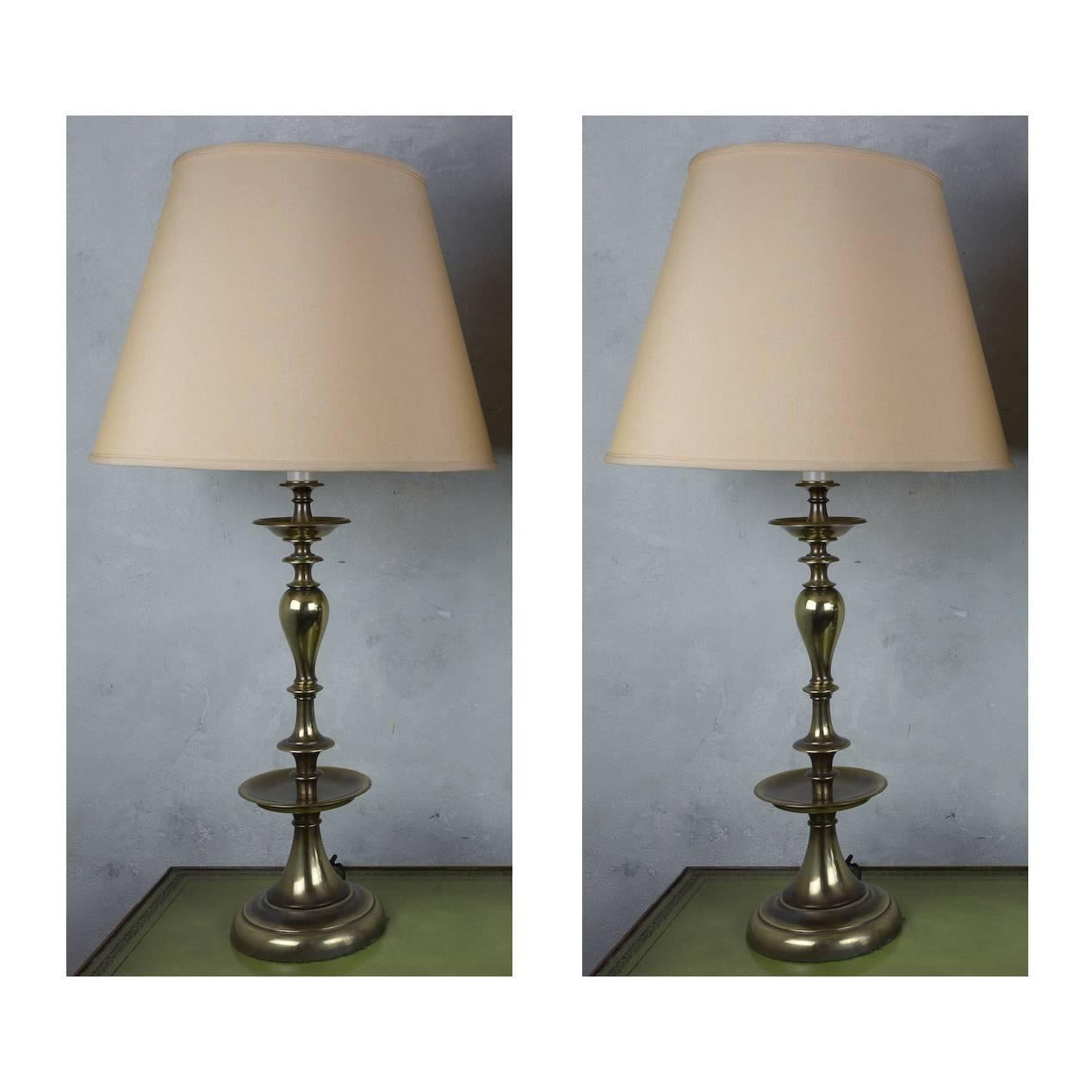 This pair of tall 1950s-1960s American mid-century brass lamps is finished in English brass. Recently rewired with double clusters and pull chains, these lamps are in very good vintage condition and their price includes hand polishing. The lamps