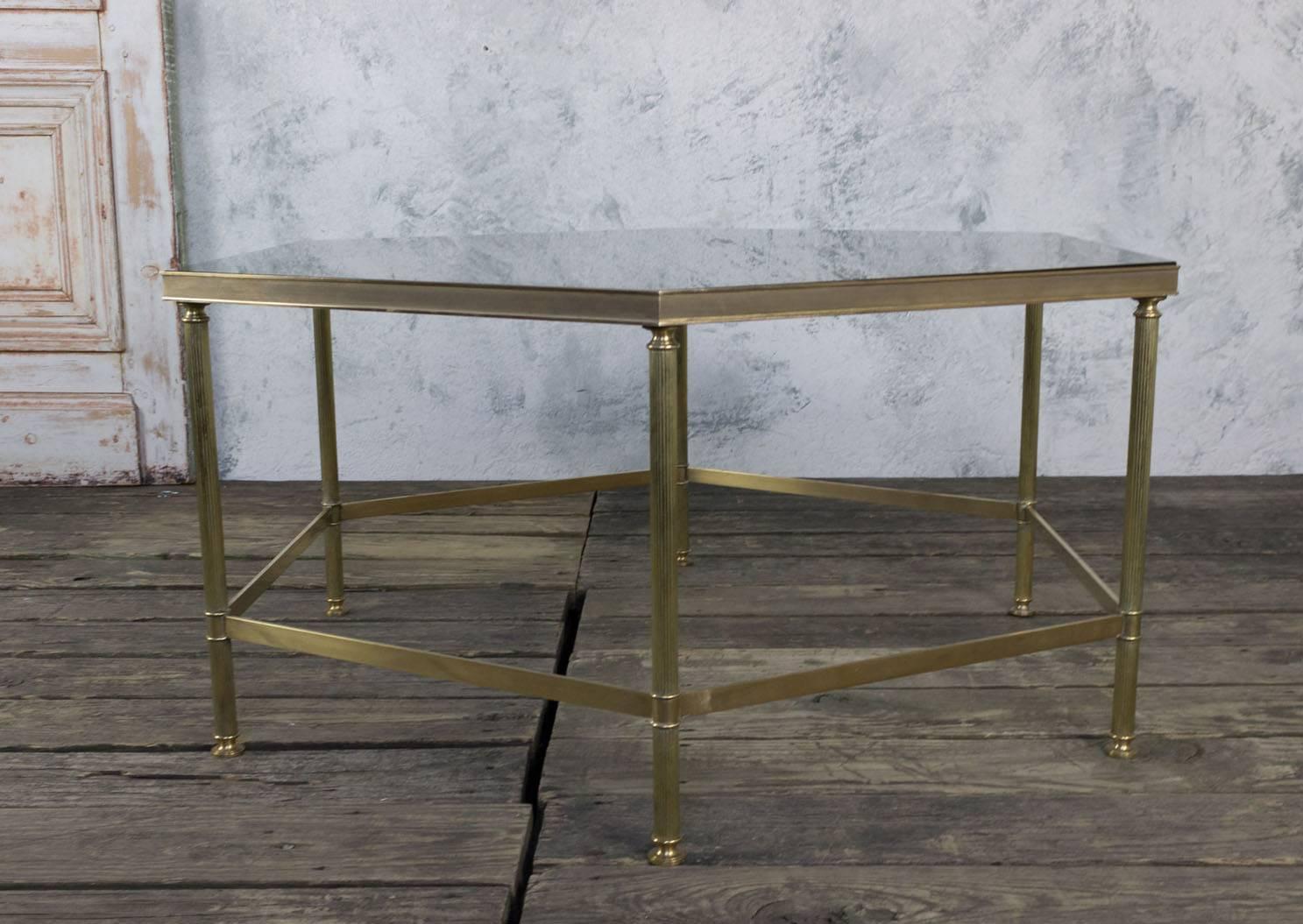 This distinctive hexagonal coffee table is a testament to French design from the 1970s. It features a smoke grey glass top that beautifully complements the mirror border, and it's all elegantly framed in brass. The table is in very good condition,