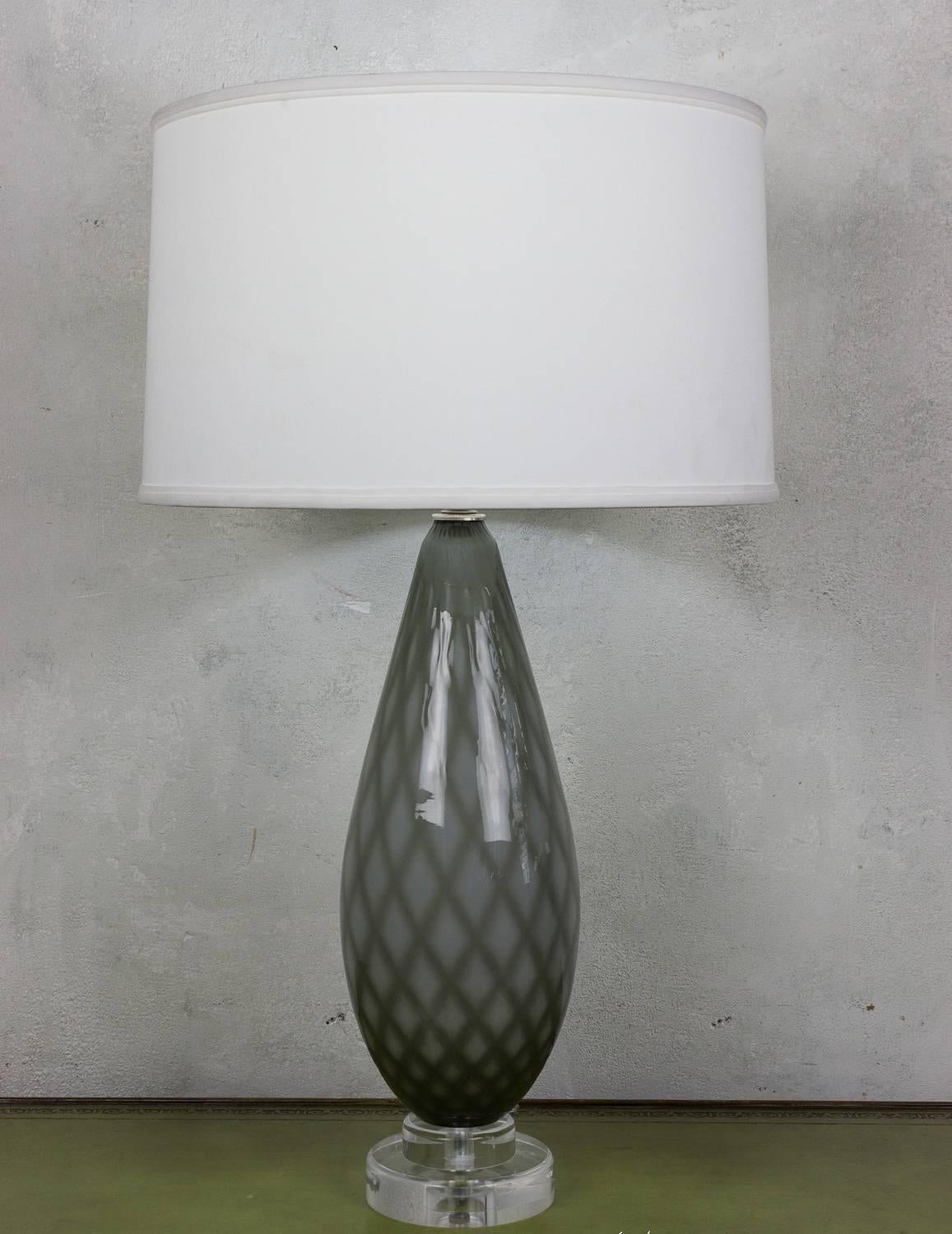 This captivating pair of table lamps originates from Italy, dating back to the 1950s. The lamps feature a remarkable diamond pattern in a cased glass design, incorporating hues of greyish-green and white. This combination brings a touch of classic