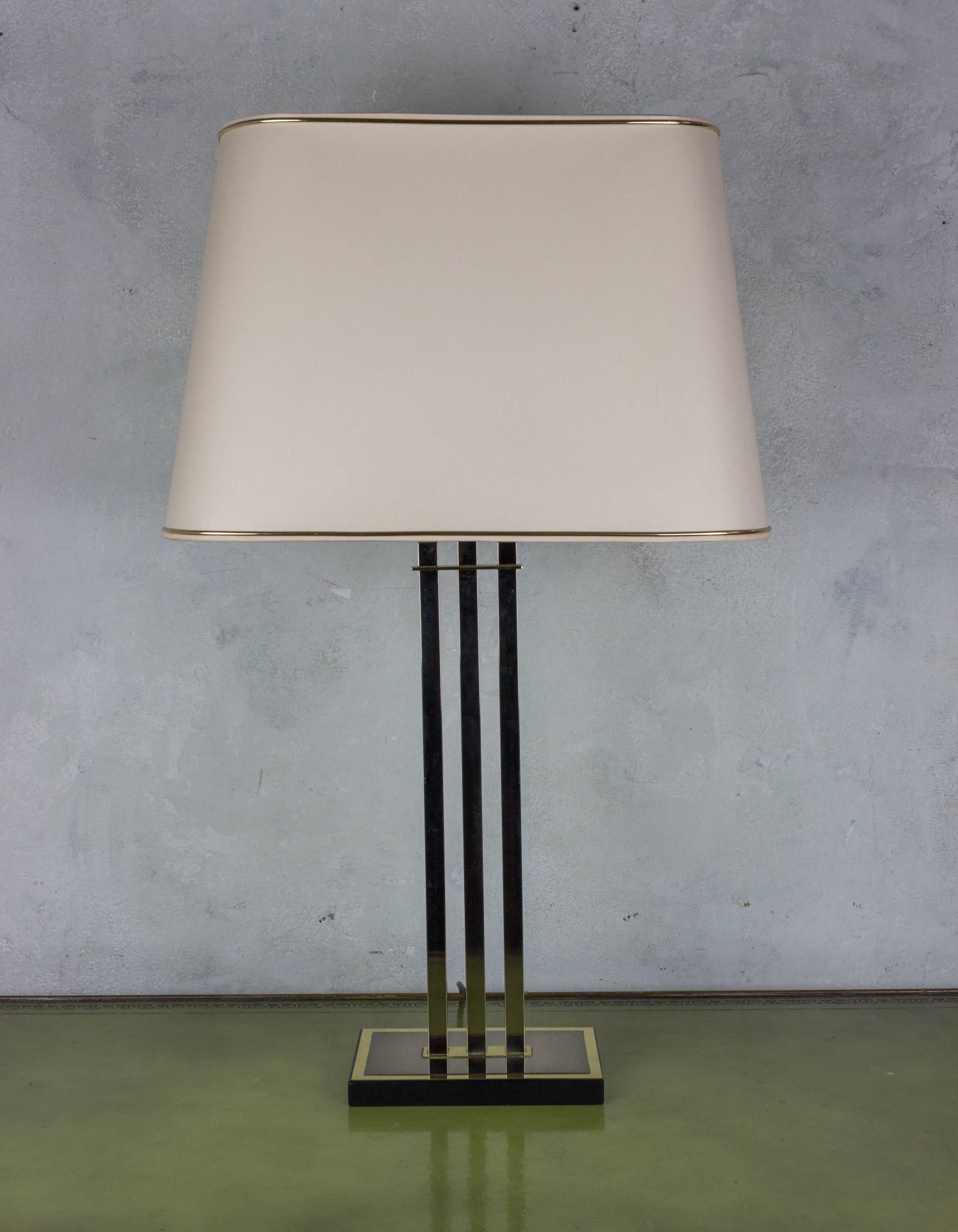 Modernist lamp with three brass vertical supports, mounted on a brass and wood base. Sold with original European shade. French, 1970s. Good vintage condition.

Ref #: LT0215-05

Dimensions: 27.5”H x 8”W x 5”D