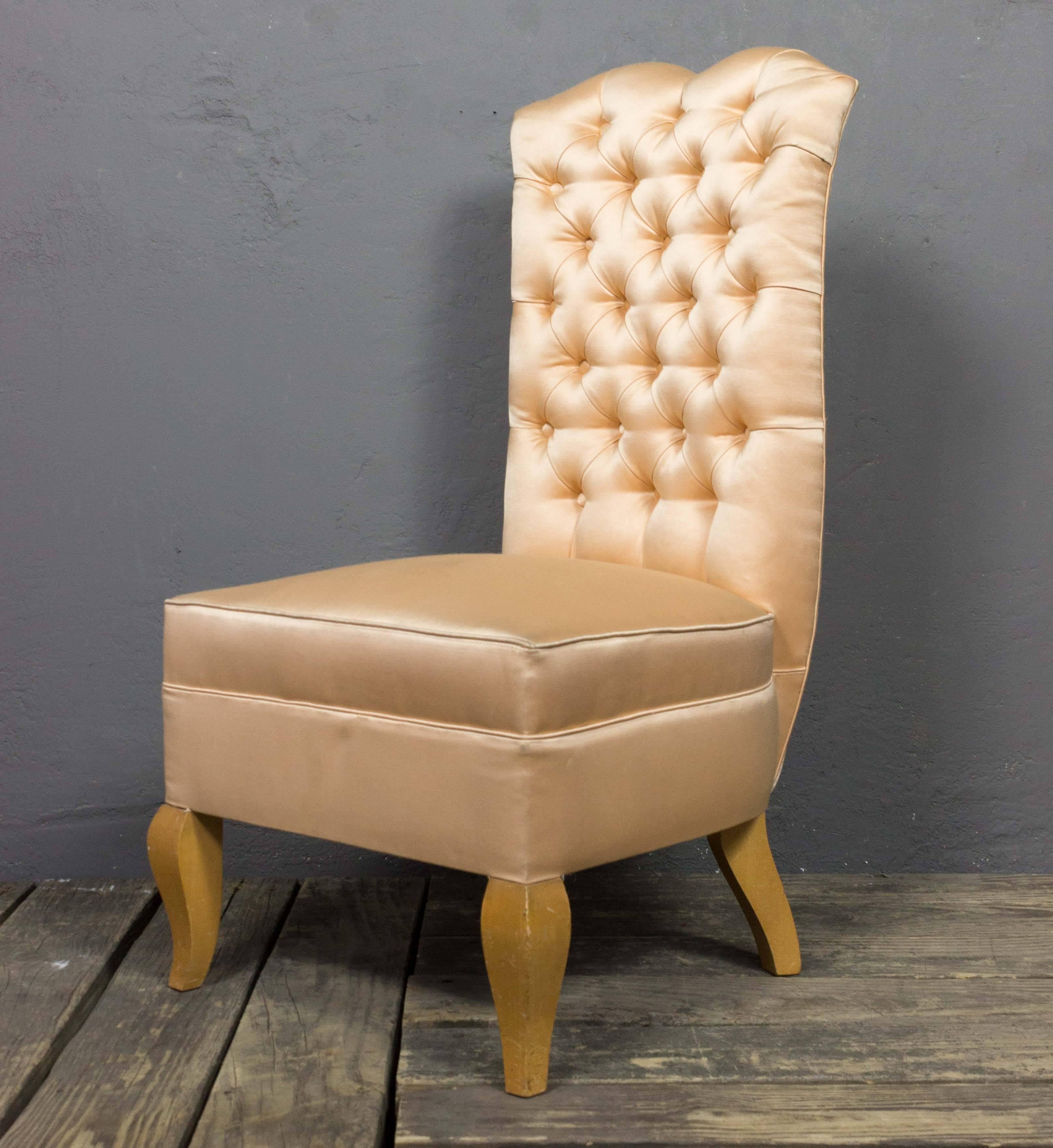 An exquisite 1940s French tufted slipper chair. This tufted high back slipper chair is a beautiful piece of French furniture from the 20th century. Upholstered in a light peach satin, it is in good condition, with some appropriate wear and tear