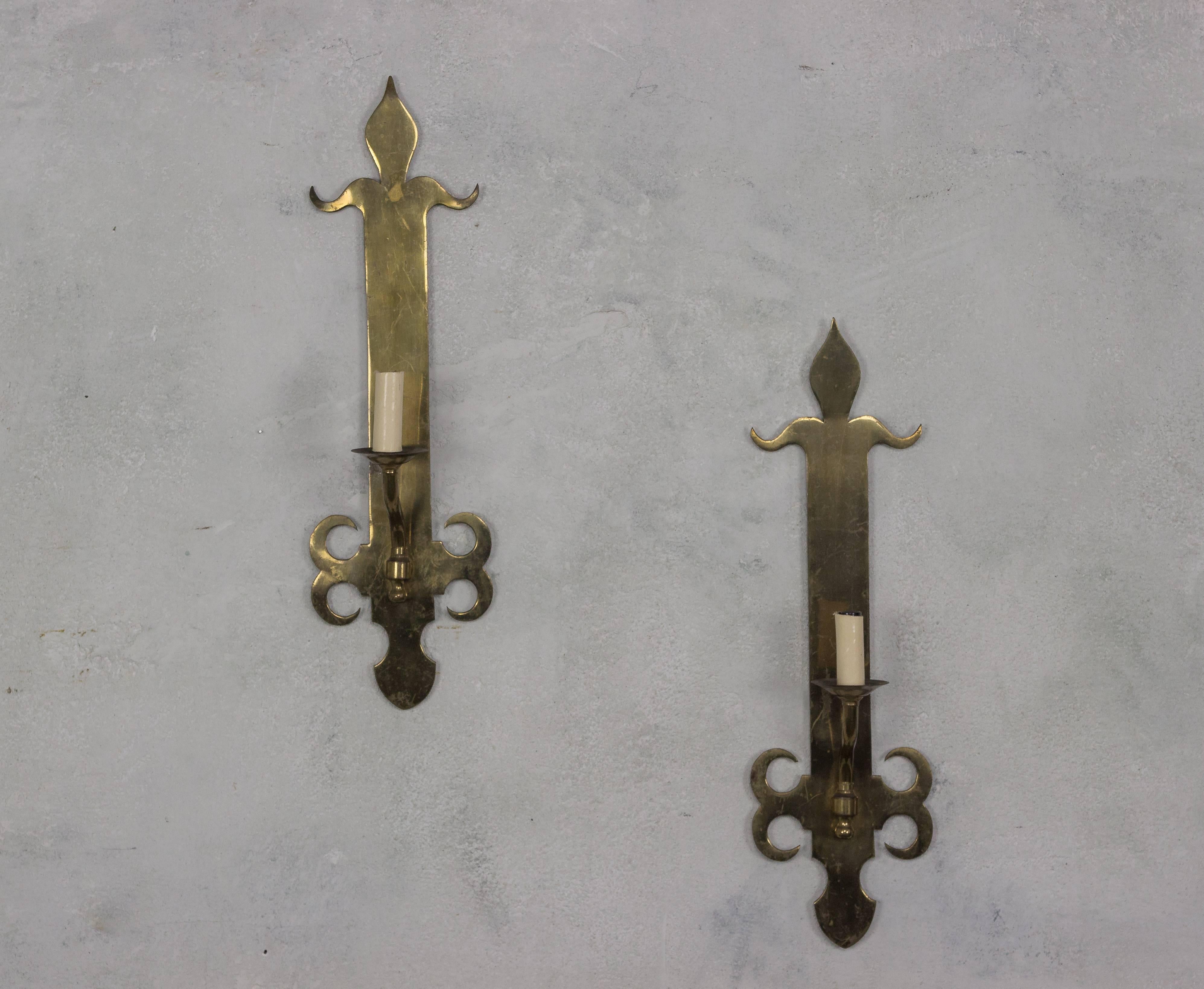 This pair of single-armed sconces, originating from France in the 1950s, is finished in English brass, lending them a timeless appeal. They are currently wired for showroom display and do not meet UL Code standards, but can be rewired to UL