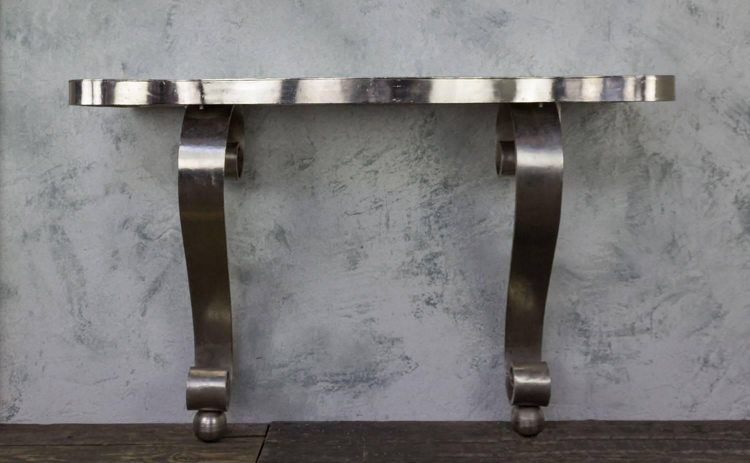 Polished Art Deco style iron console table having serpentine top supported on scroll form legs.