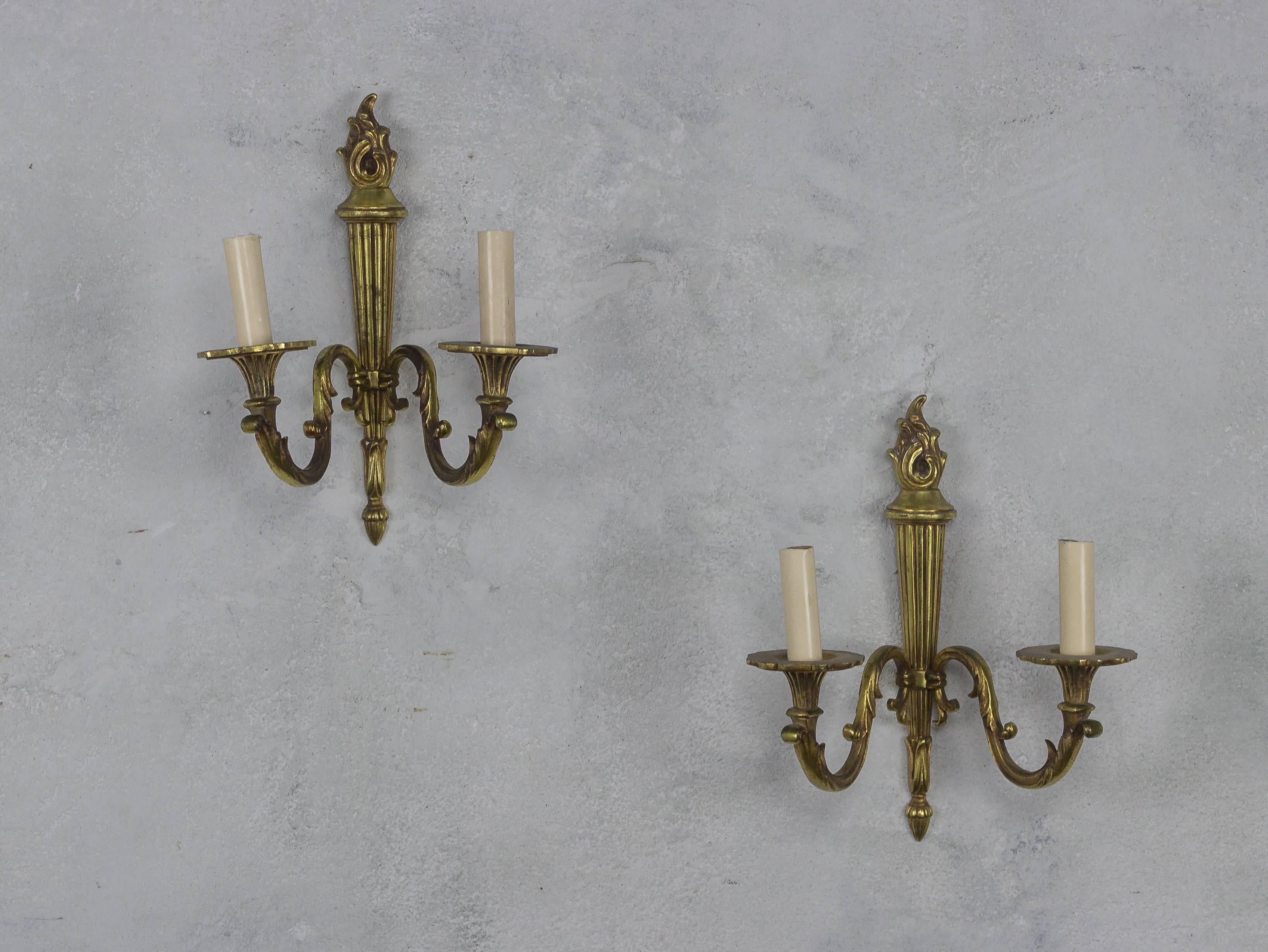 This pair of French 1940s gilt bronze two armed sconces exudes the elegance and sophistication of the neoclassical Louis XVI style. These small scale sconces boast a double arm lighting system, elegantly mounted on a traditional central stem adorned