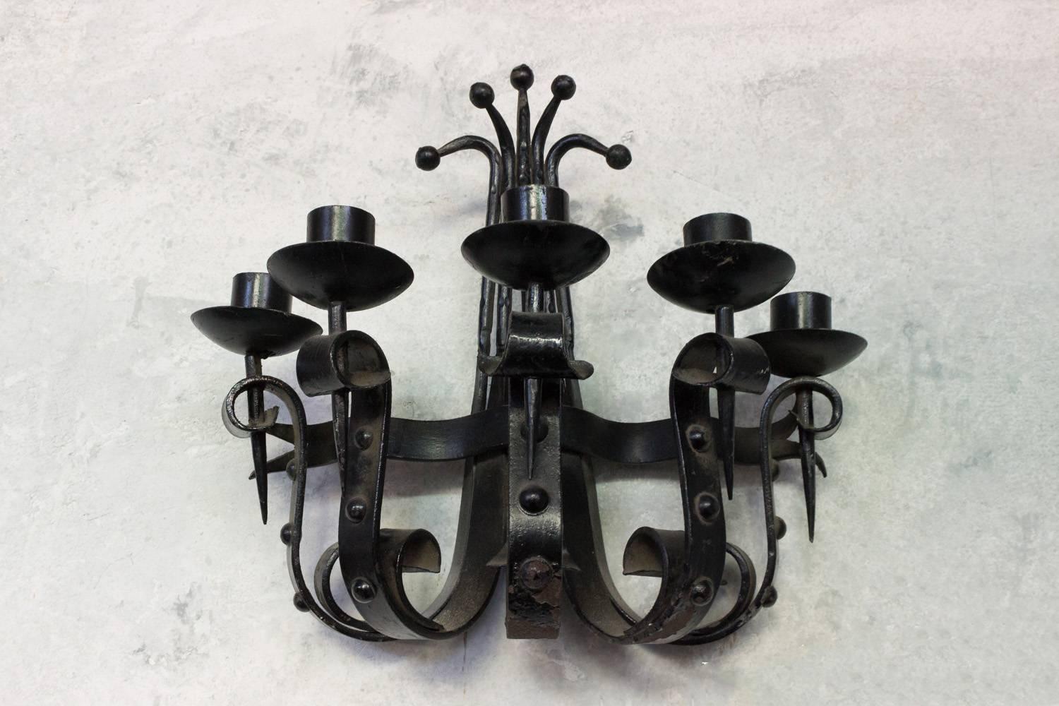 This impressive French 1940s single black wrought iron five-armed sconce is a true work of art. The large sconce boasts hand-forged iron scrolled candle holders mounted on scrolled arms that culminate in elegant upper curved ball motifs,