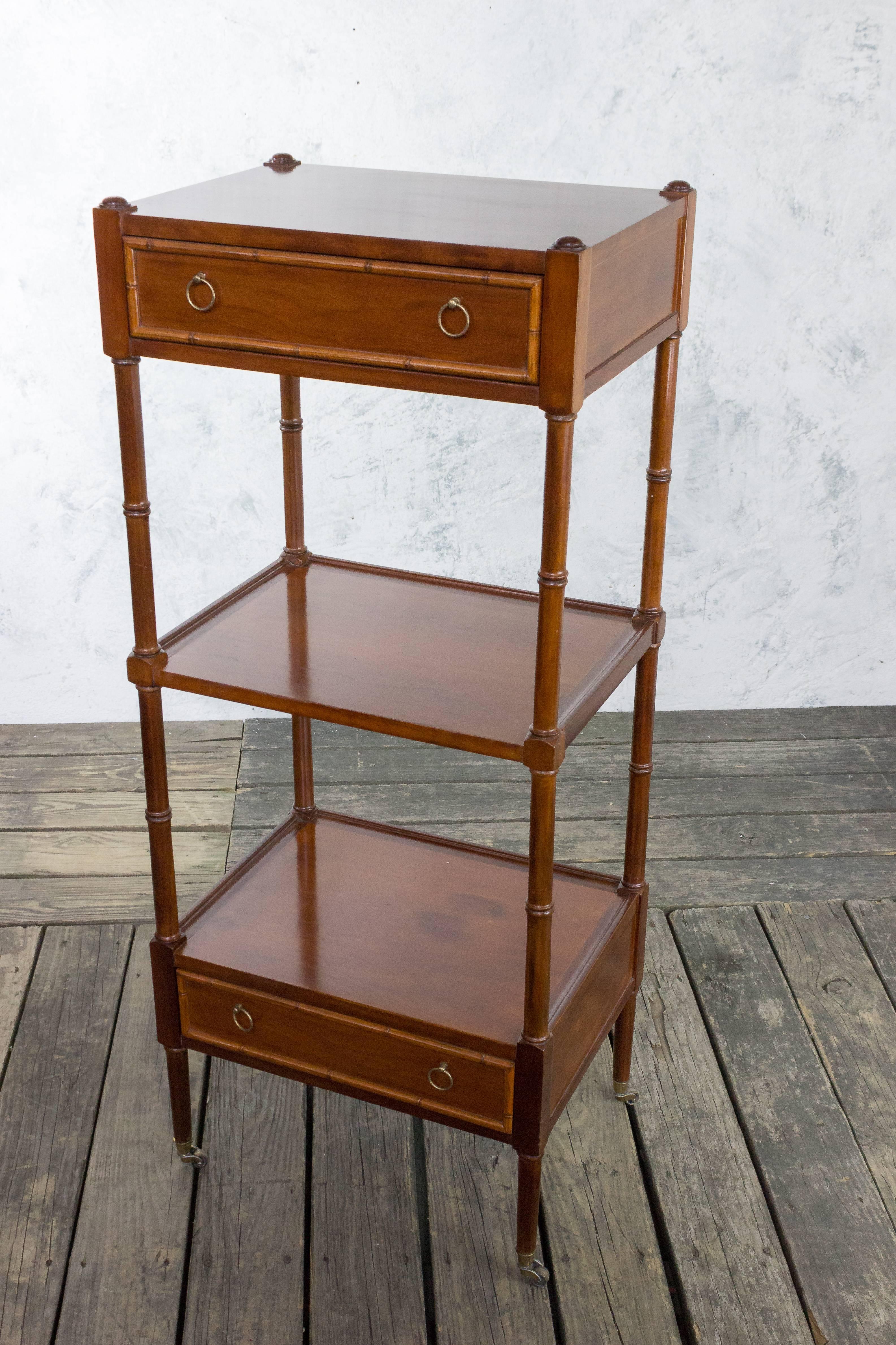 This American 1940s mahogany etagere features three tiers with drawers on two of the tiers. The brass pulls and sabot draw attention to the detailed carvings on the drawers and legs, adding a touch of elegance to its overall appearance. Equipped