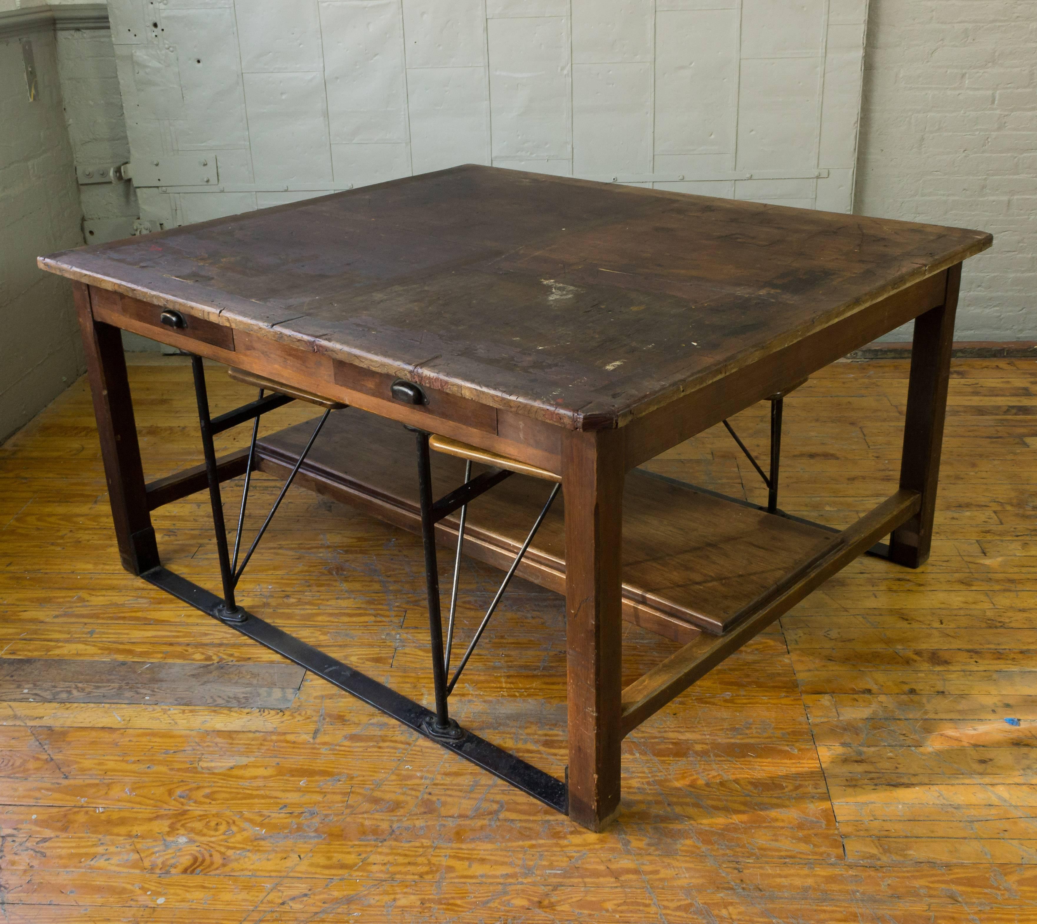 Very amazing Industrial table with twinkle drawers on seat sides. This piece has attached wooden seats that can swing in or out on metal framework. The table is of heavy wood and has a nice vintage patina.