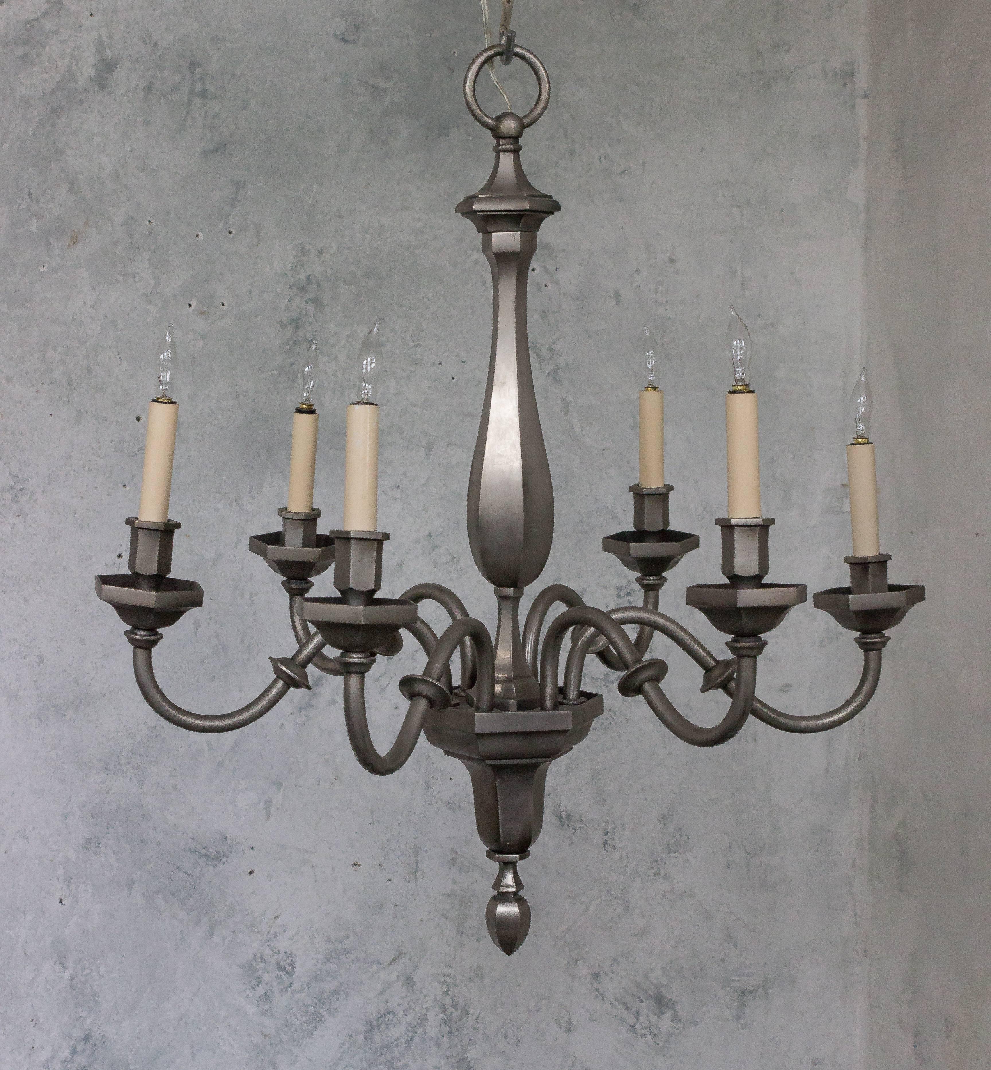 This French chandelier from the 1940s is a striking combination of bronze and metal. Designed in a neoclassical style, it features six arms that gracefully extend from its center. The chandelier has recently been refinished in a warm, antiqued