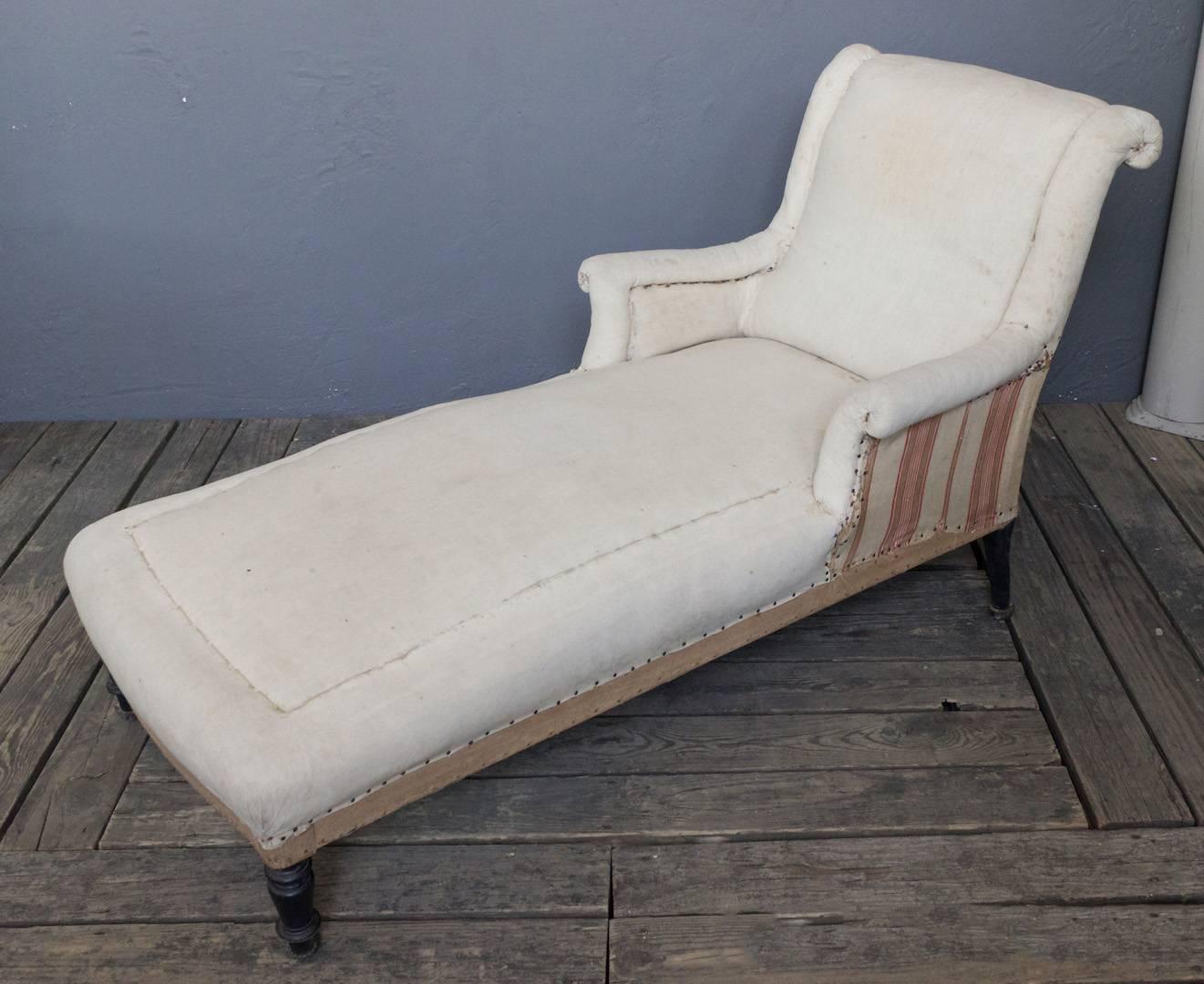 19th century French chaise longue with curved arms and scrolled back resting on turned wood legs. Sold as is.