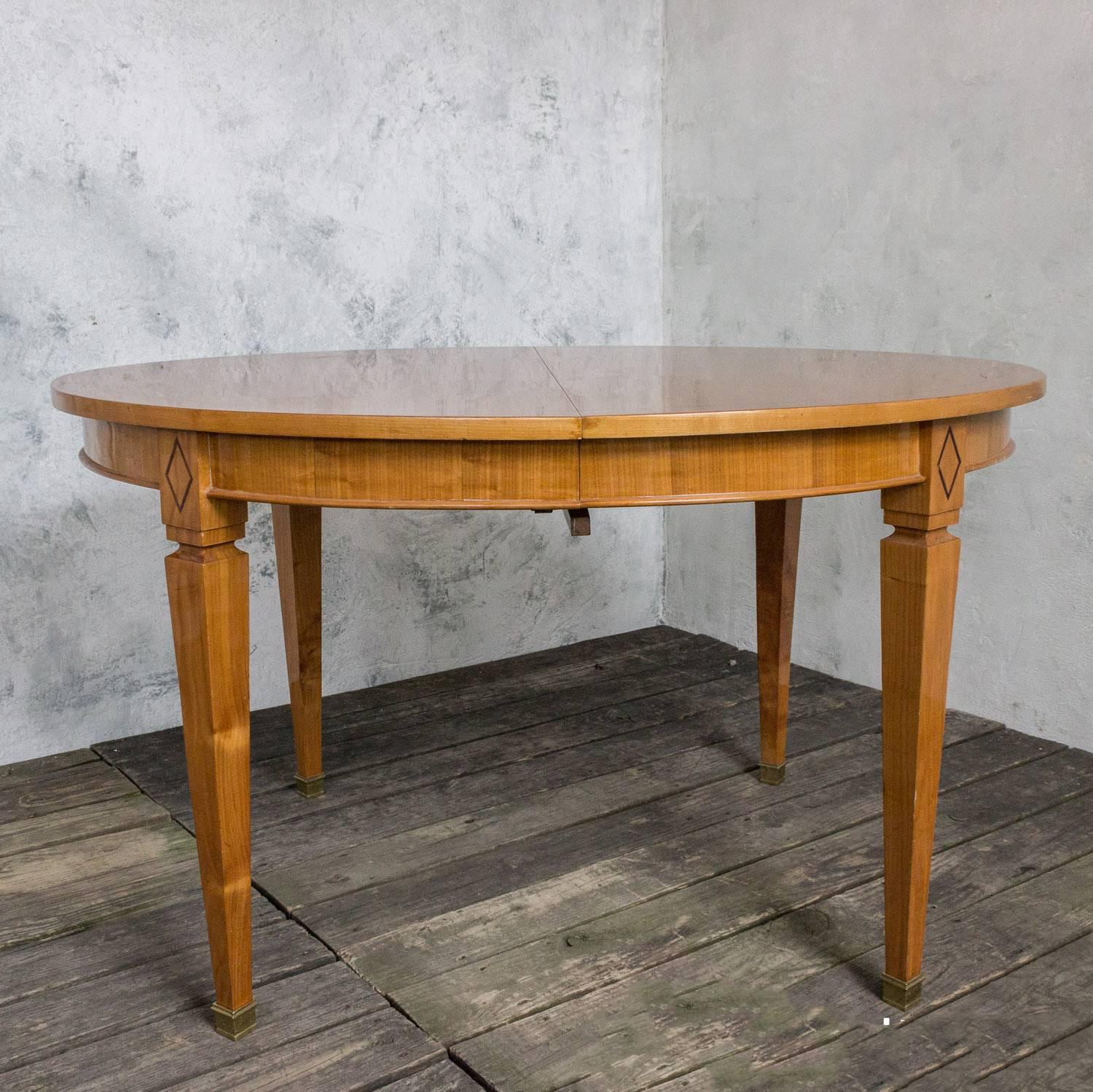 Beautiful French 1940s oval cherry dining table. It has an ebony inlay along the perimeter of the table top and a diamond design inlay on the legs. The legs also have a brass sabots. Measure: It has one 18