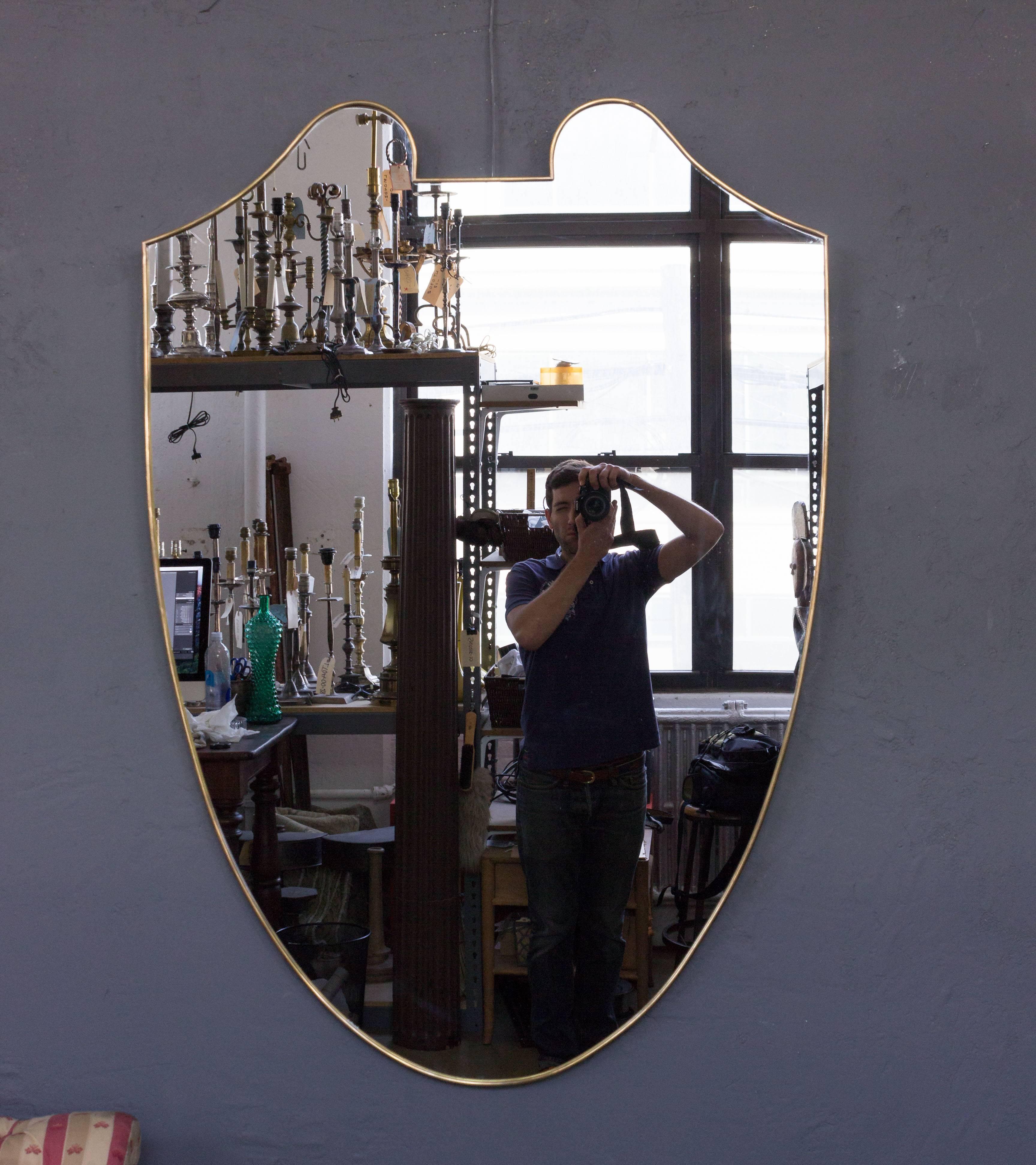 Large 1960s Italian brass framed mirror in the form of a shield.