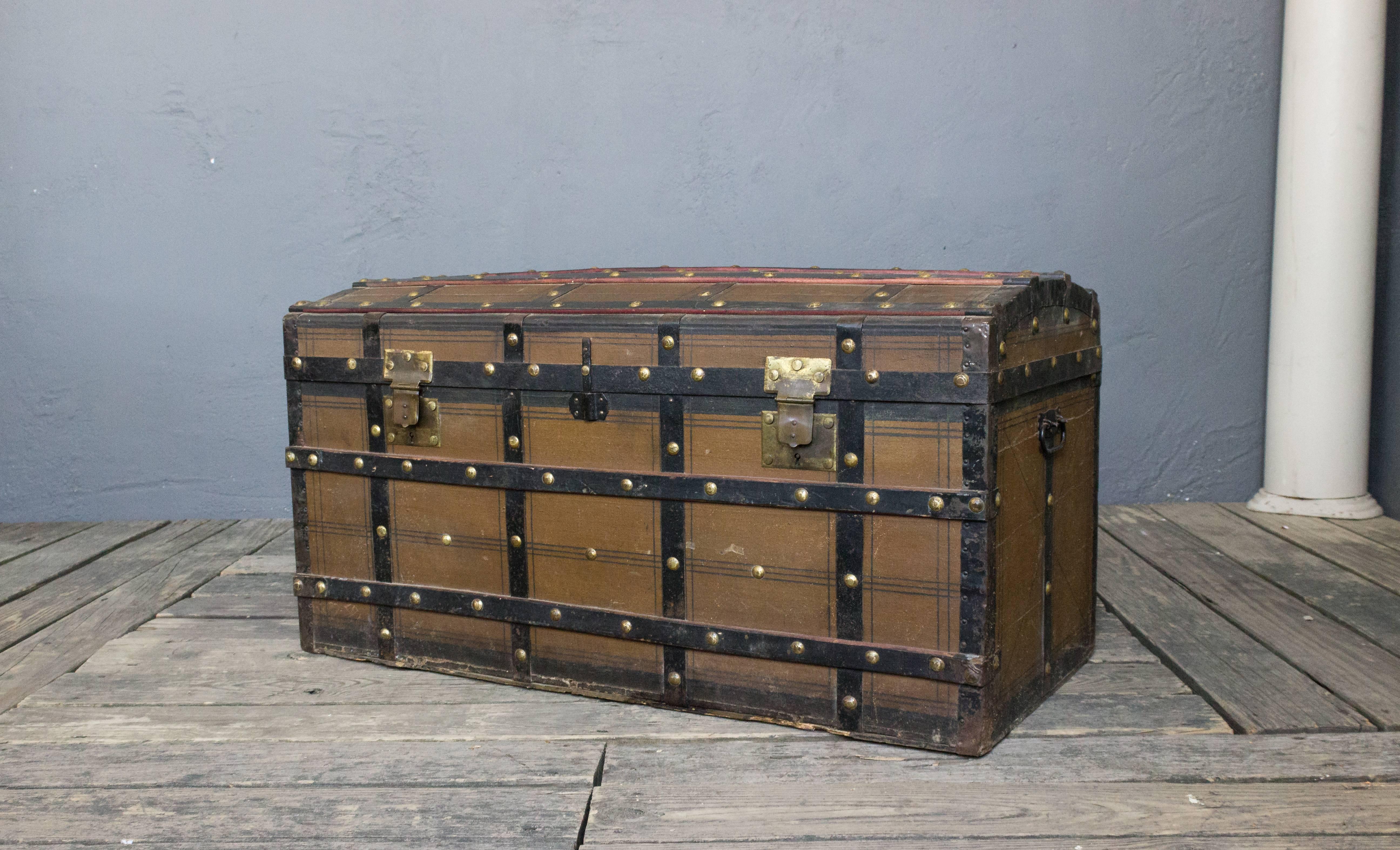 French 1920s steamer trunk with brass studs on a wooden ribbing. The clasps are also brass. It has iron handles on the sides.
