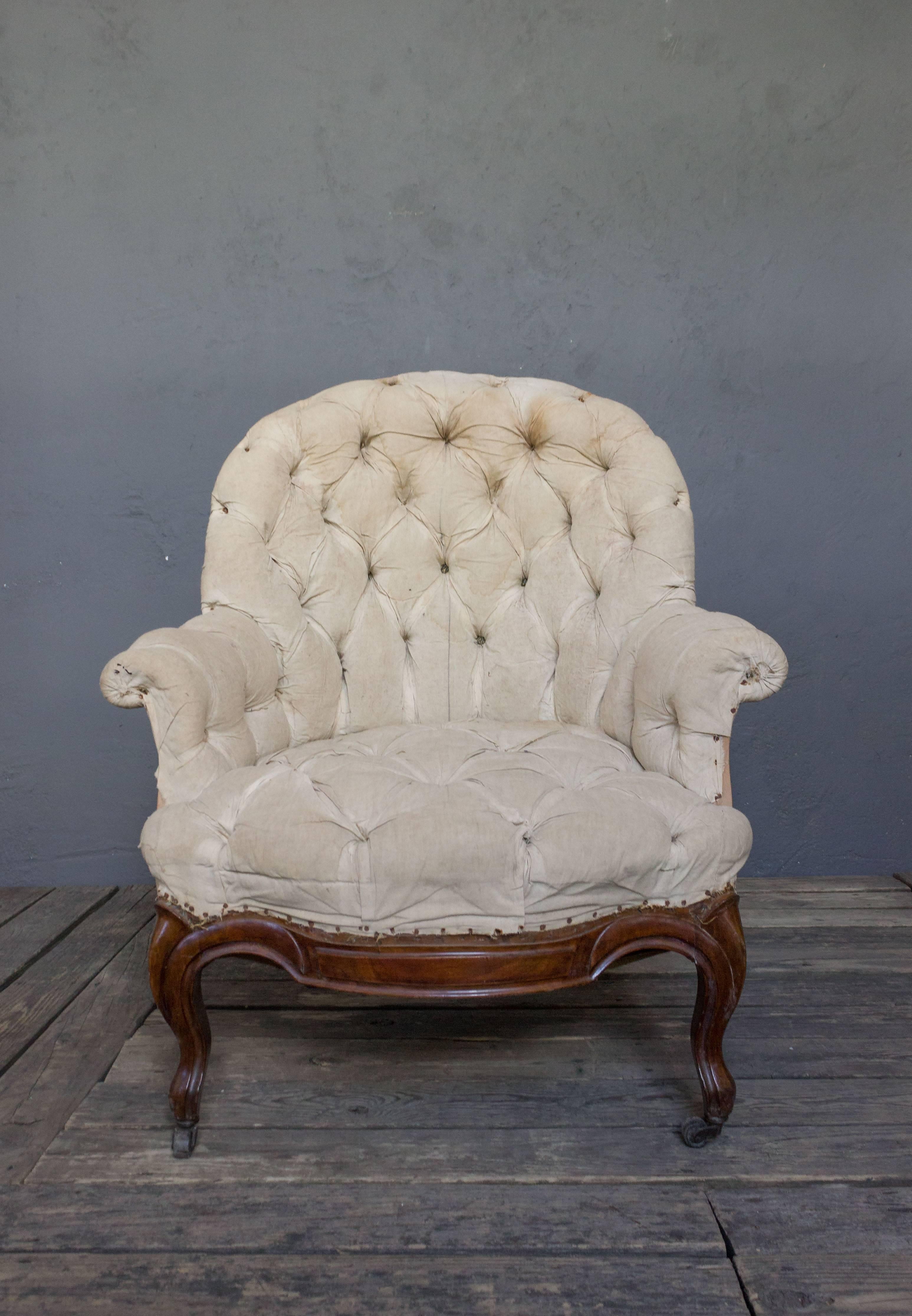Pair of large French Napoleon III armchairs with polished cabriole wooden legs and trim. These chairs are heavily tufted with high rounded backs and rolled arms.