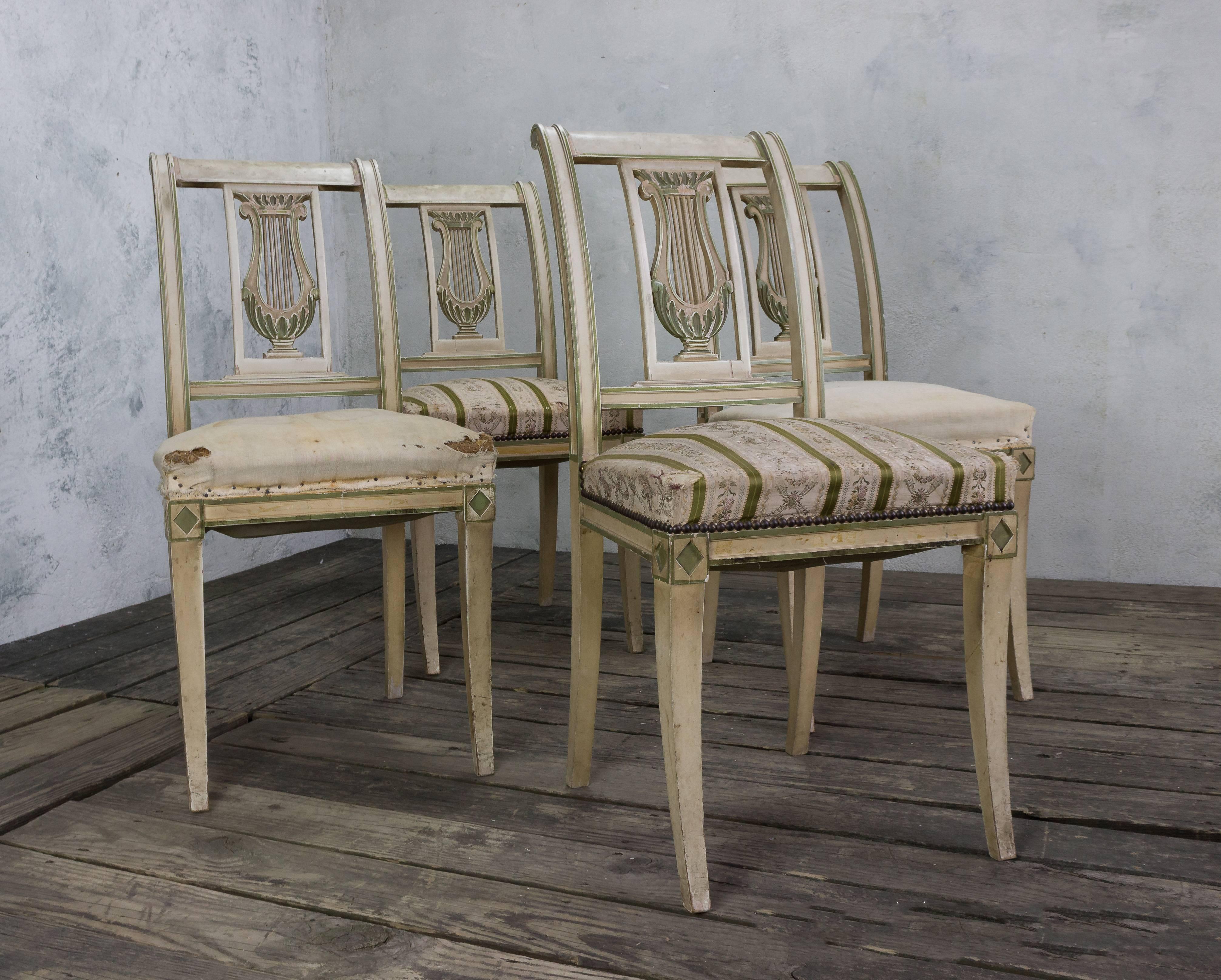 An elegant set of four Neoclassical style French painted dining room chairs, circa 1920. This stunning set of Neoclassical style French dining room chairs is sure to bring beauty and sophistication to any home. The intricate frames feature lovely