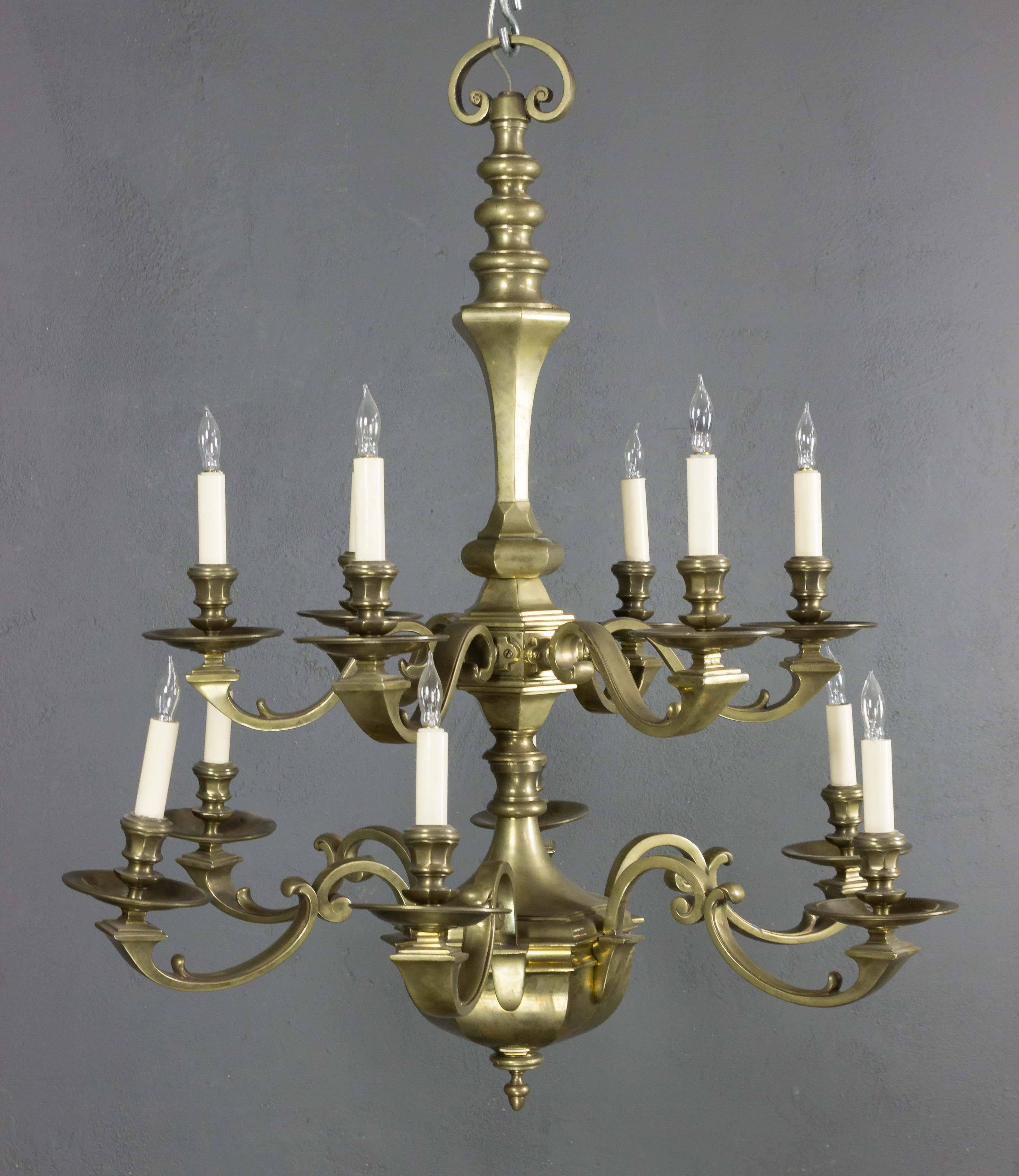 This stunning French chandelier from the 1940s is a captivating blend of bronze and metal. Designed in a neoclassical style, it features two tiers of lights with six arms on each tier, creating a striking visual impact. The vintage piece is in very