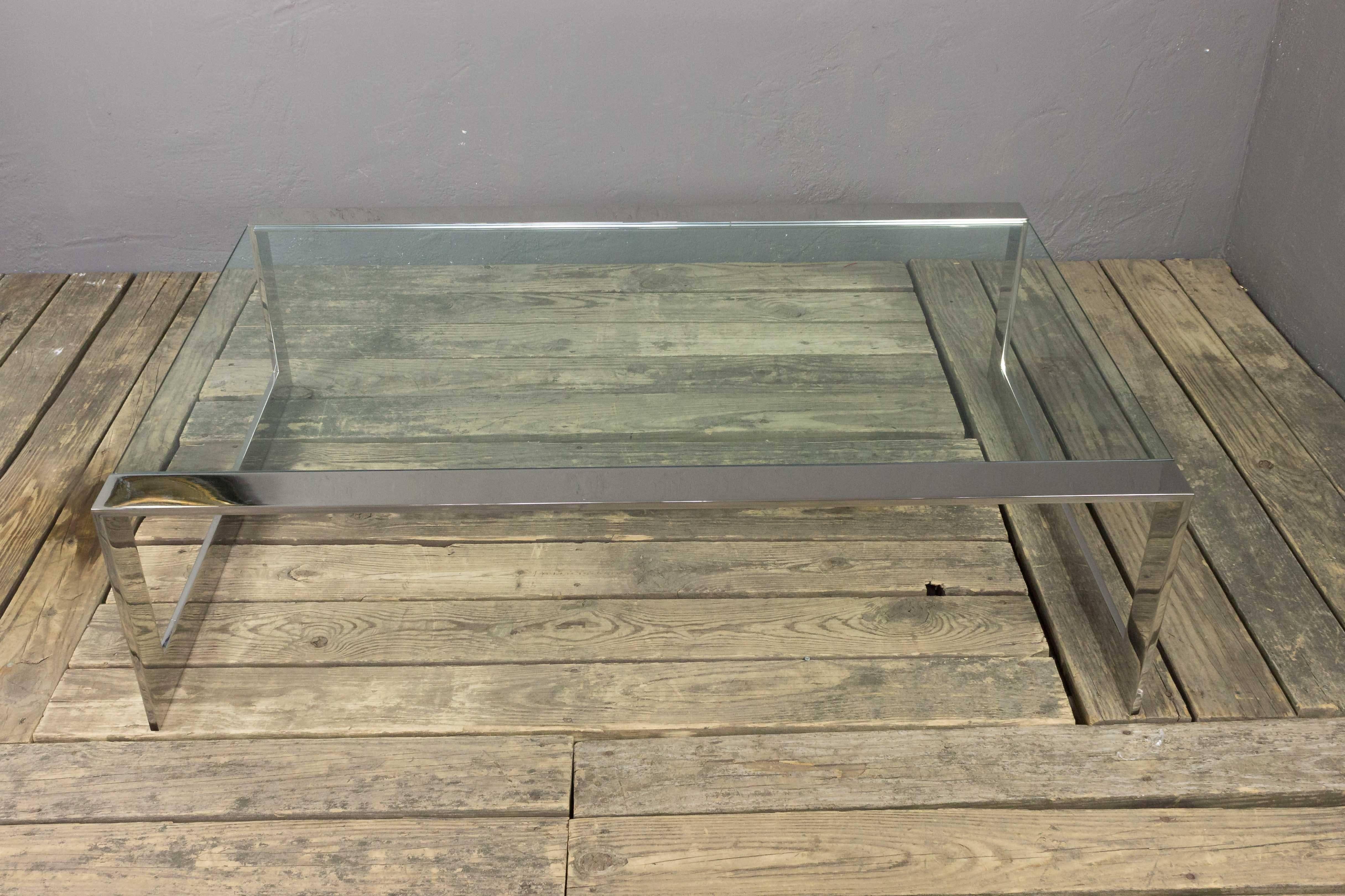 Cette table basse en acier inoxydable poli est dotée d'un plateau en verre transparent encastré, ajoutant une touche élégante et contemporaine à tout espace de vie. En très bon état, le cadre a été récemment poli, ce qui lui donne un aspect propre