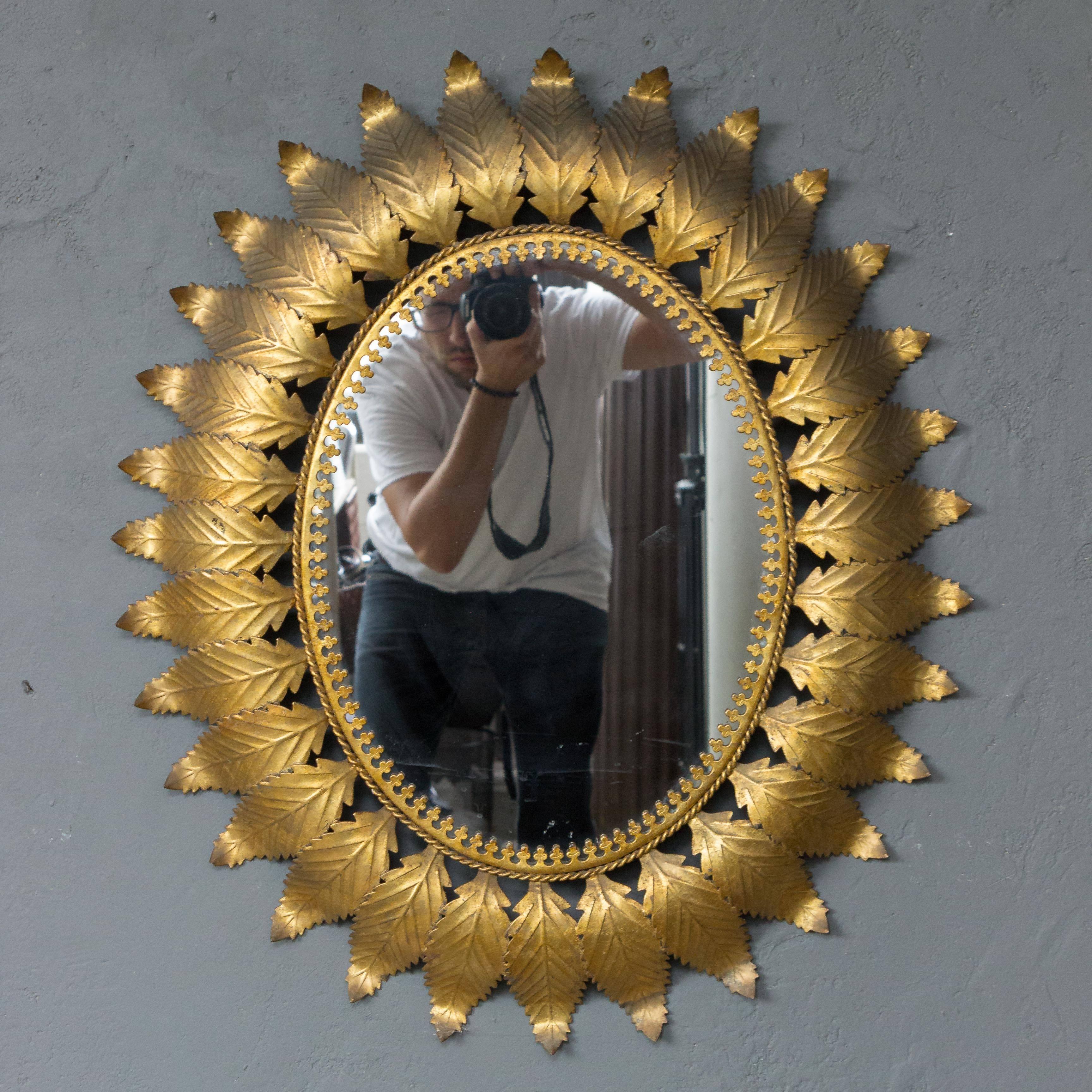 Oval gilt metal mirror with leaf design rays.