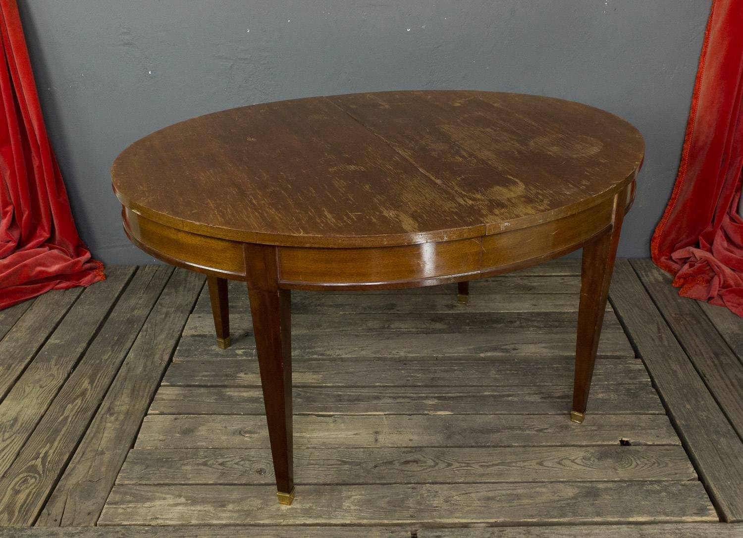 French 1940s mahogany veneered oval dining table with the brass sabot. The table can open to 90